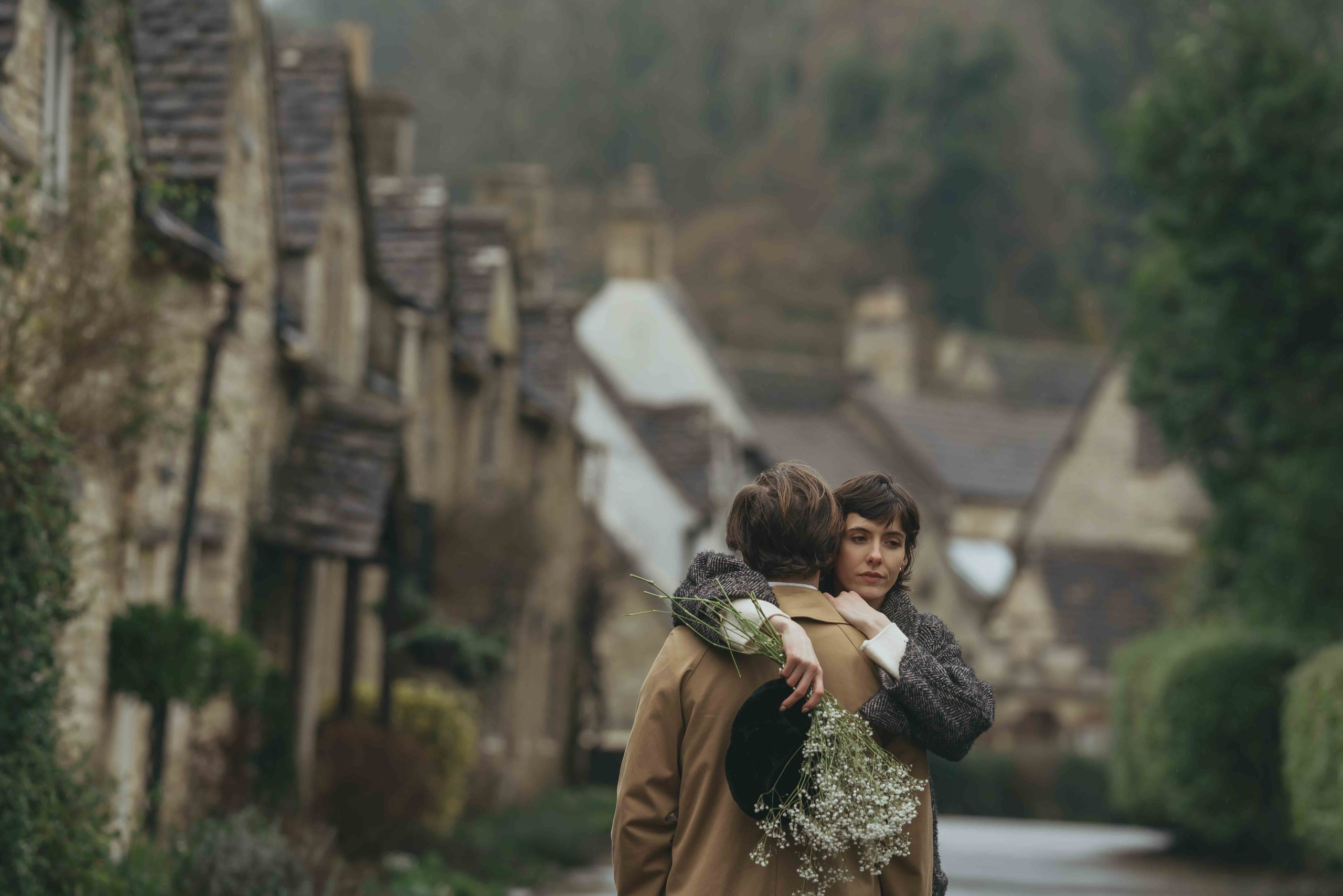 scenic view of Cotswolds village Castle Combe with couple walking in rainy atmosphere
