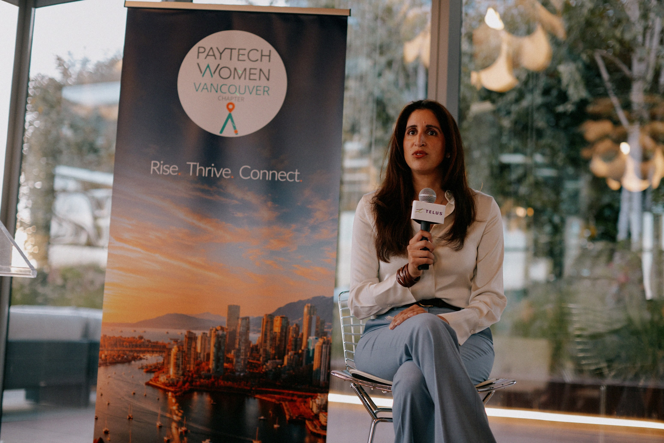 Panelist speaking beside the PayTech Women Vancouver Chapter banner at The Career Curve