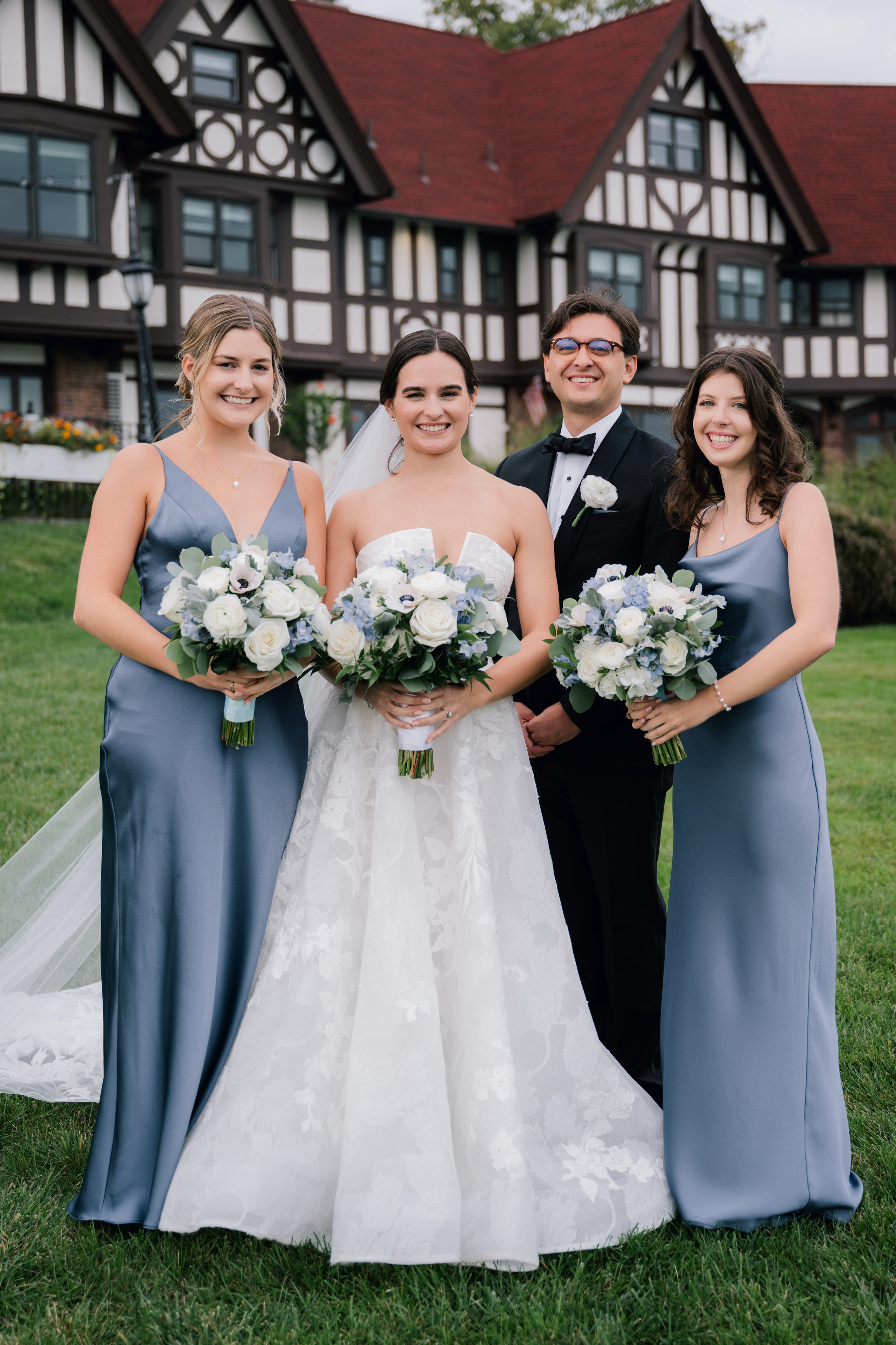 a bride and her bridesmaids pose for a photo in front of the tudor house