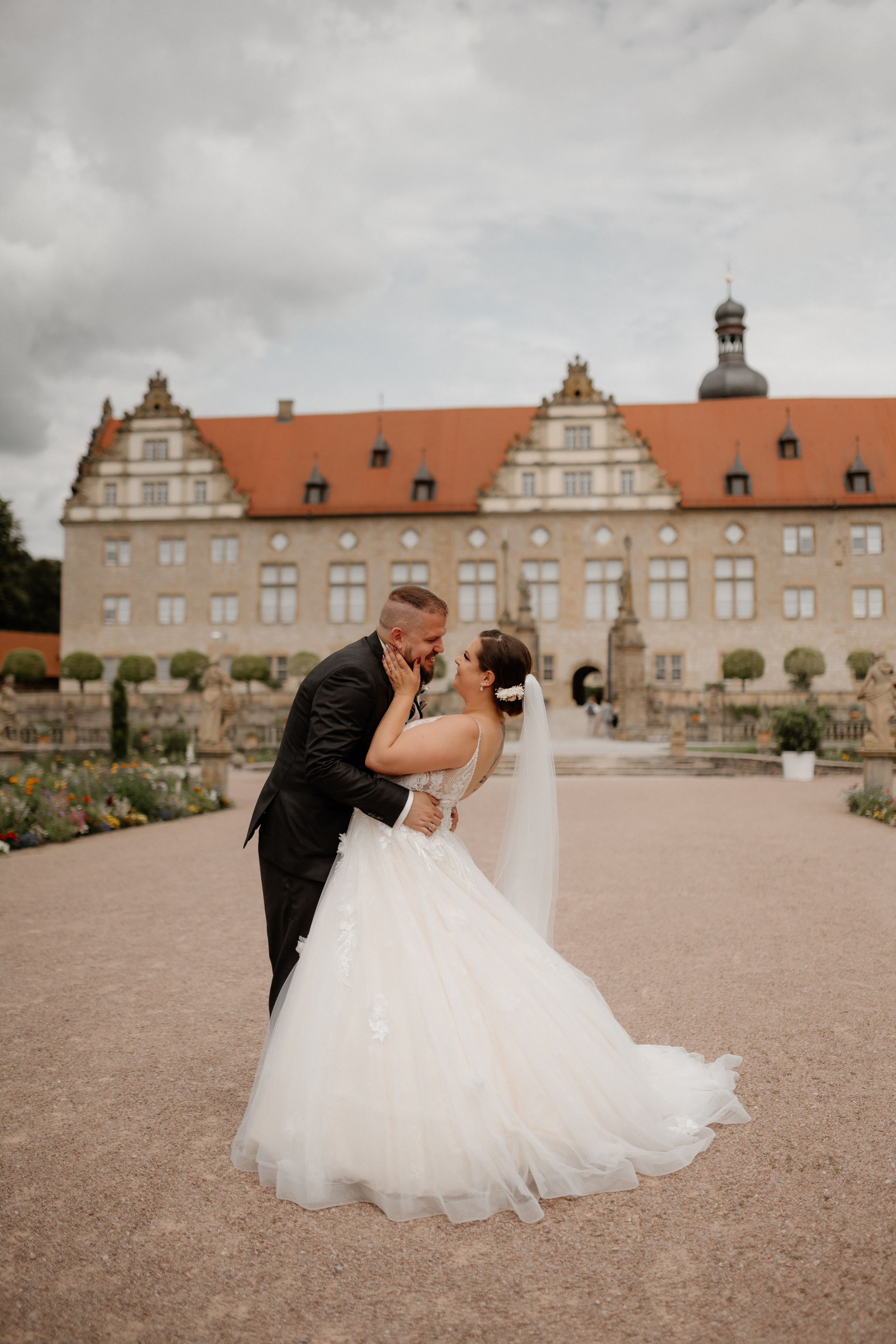 Julia & Dominik in romantischer Umarmung vor der Schlosskulisse