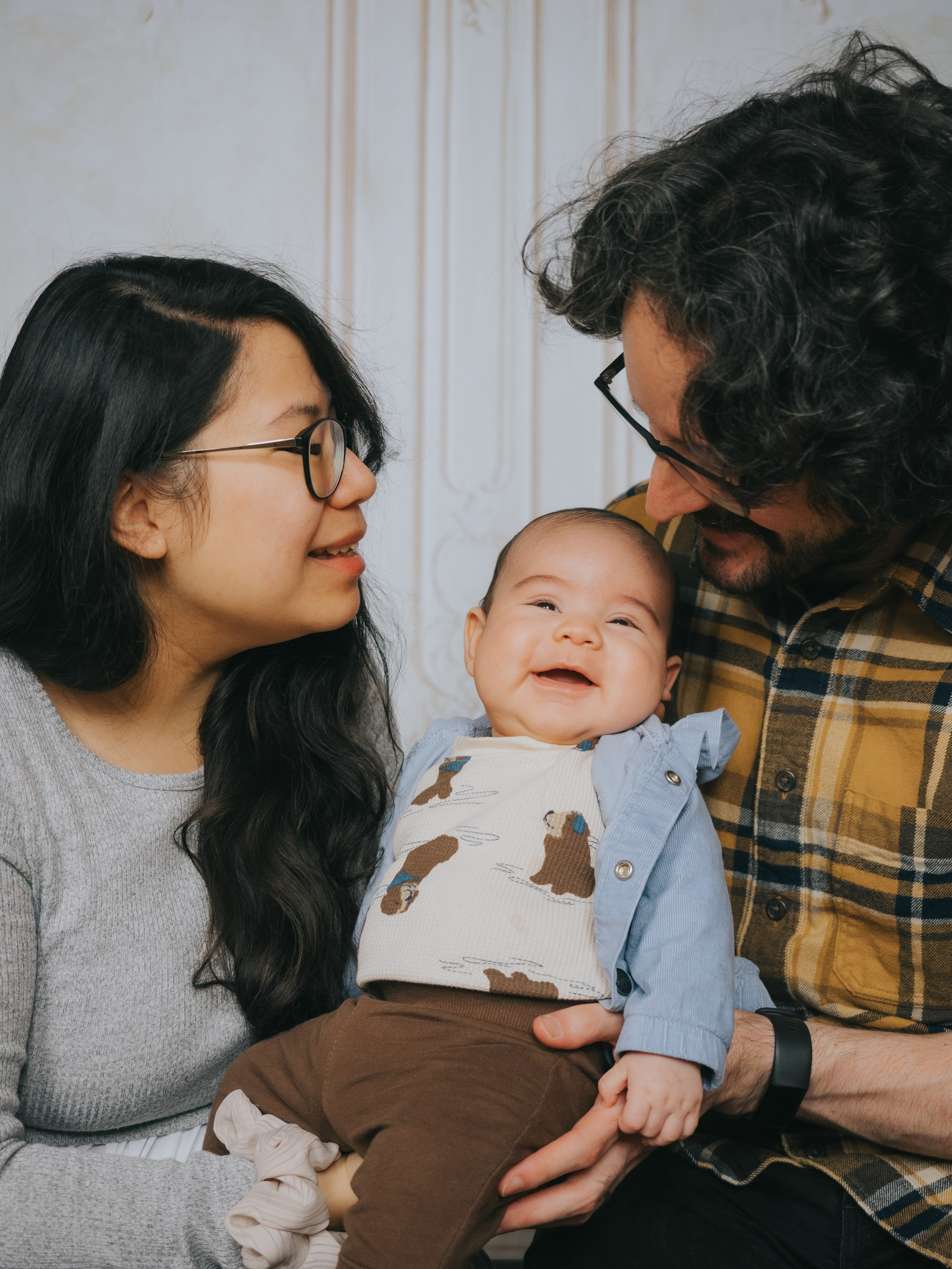Nourrisson souriant pendant que ses parents le regardent.
