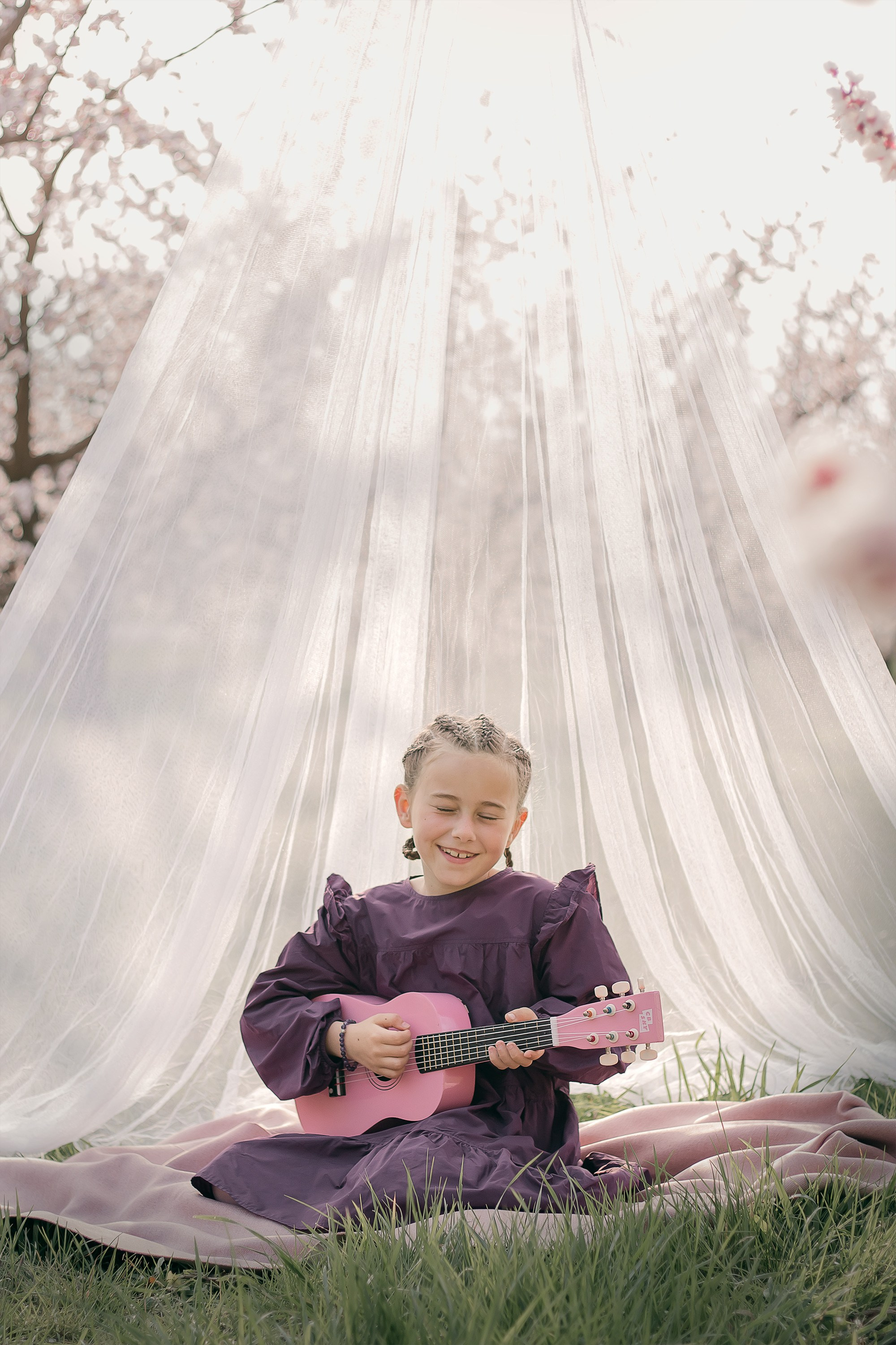 Une petite fille joue de la guitare dans un verger en fleurs en Provence, en France.
