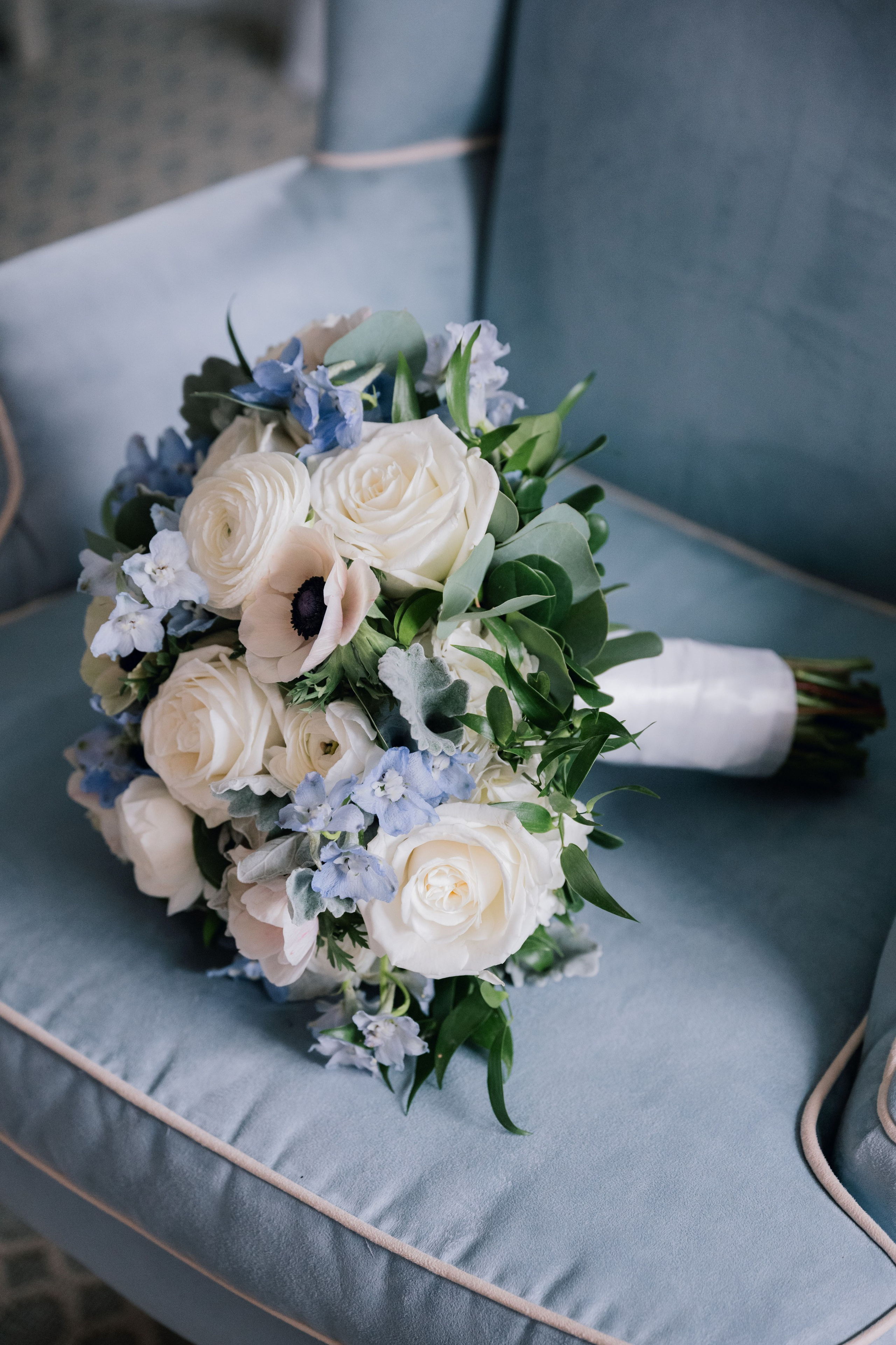 a bouquet of white roses and blue flowers on a blue chair