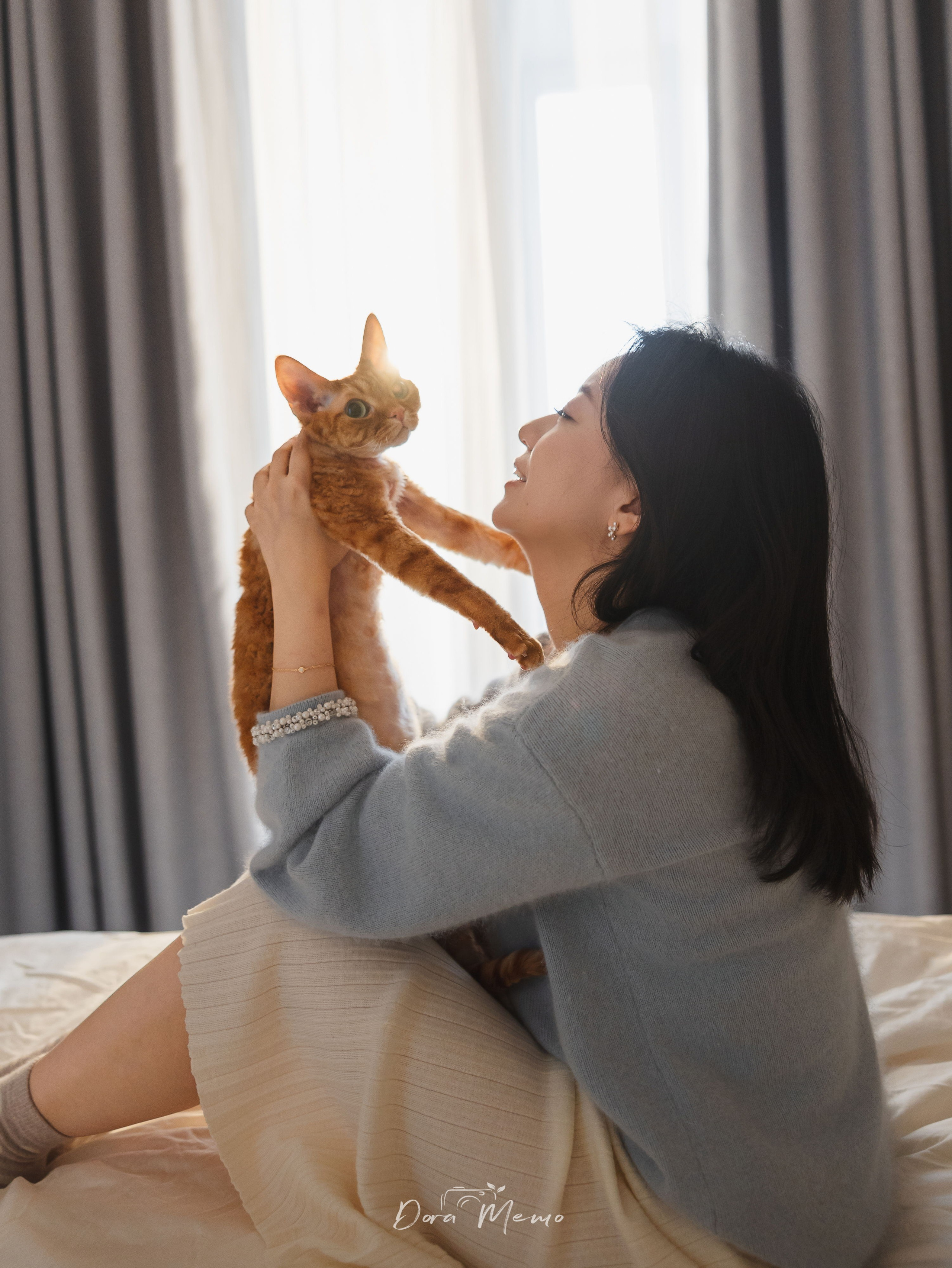 Devon Rex cat and owner playing together in soft window light during a home pet photoshoot