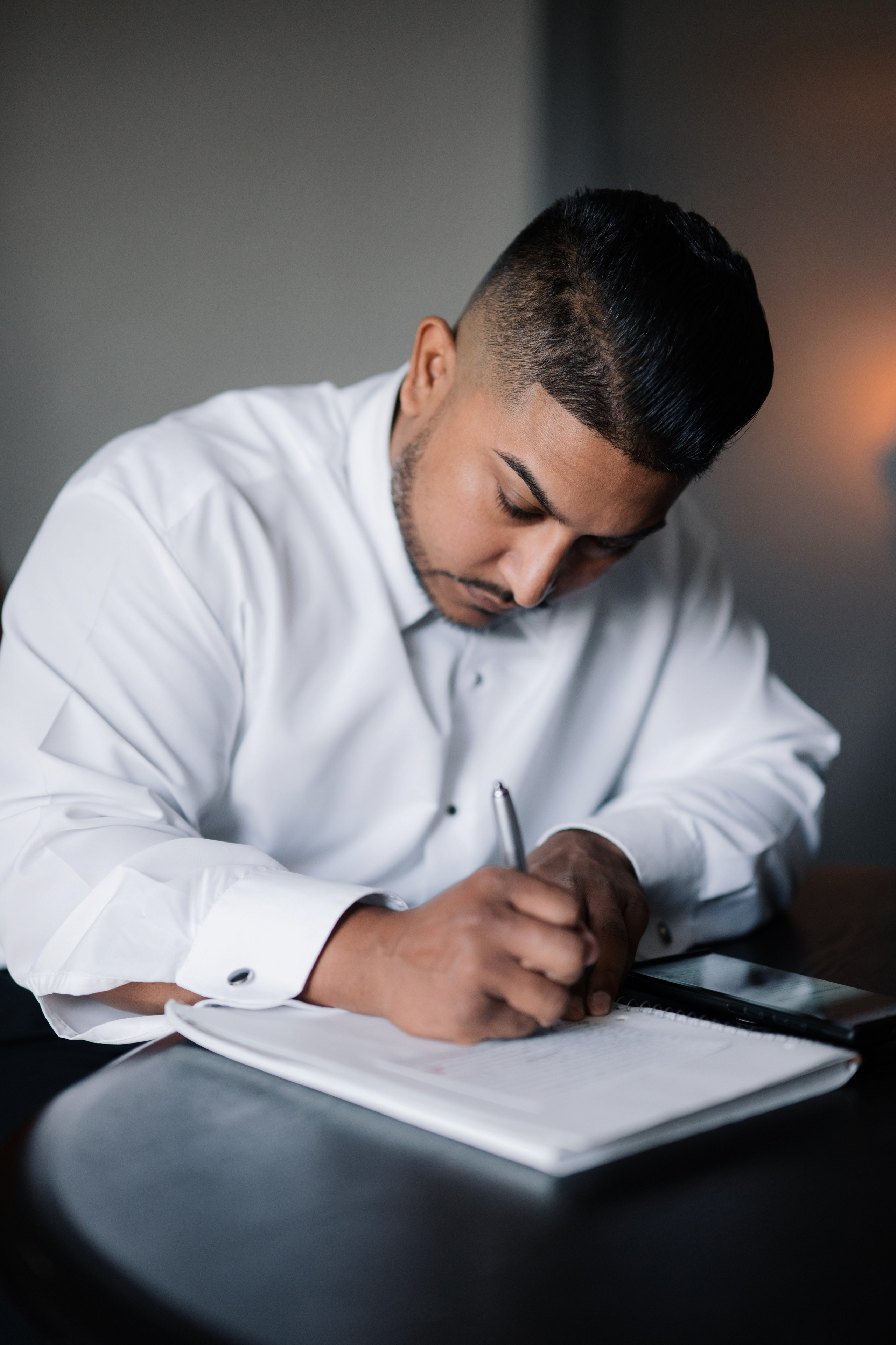 a man in a white shirt writing on a piece of paper