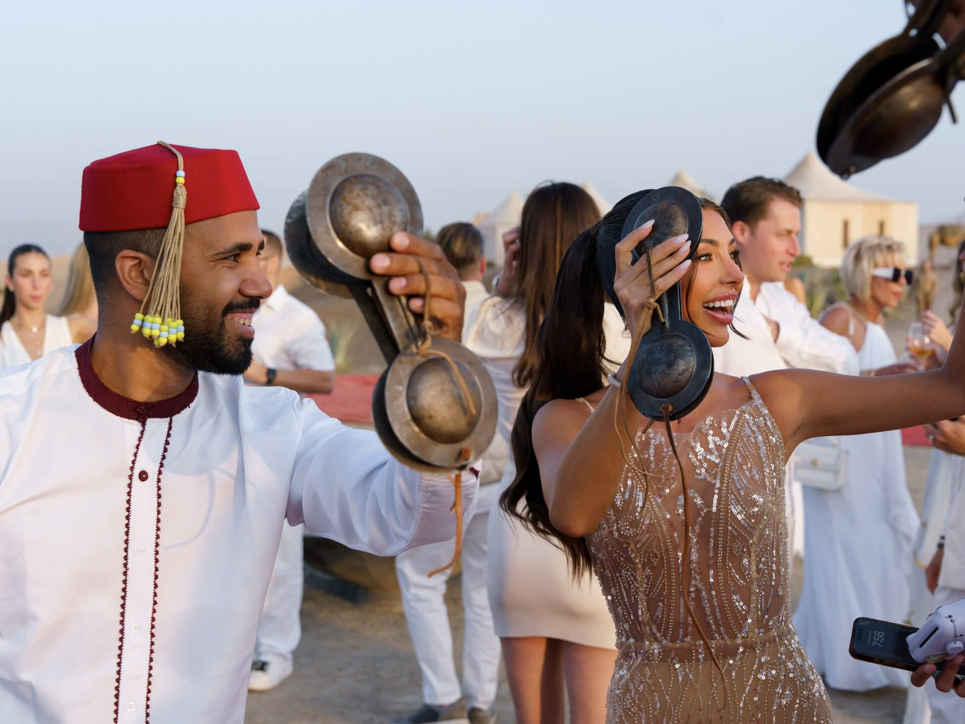 Bride and guests playing hand cymbals during luxury desert wedding reception, Morocco