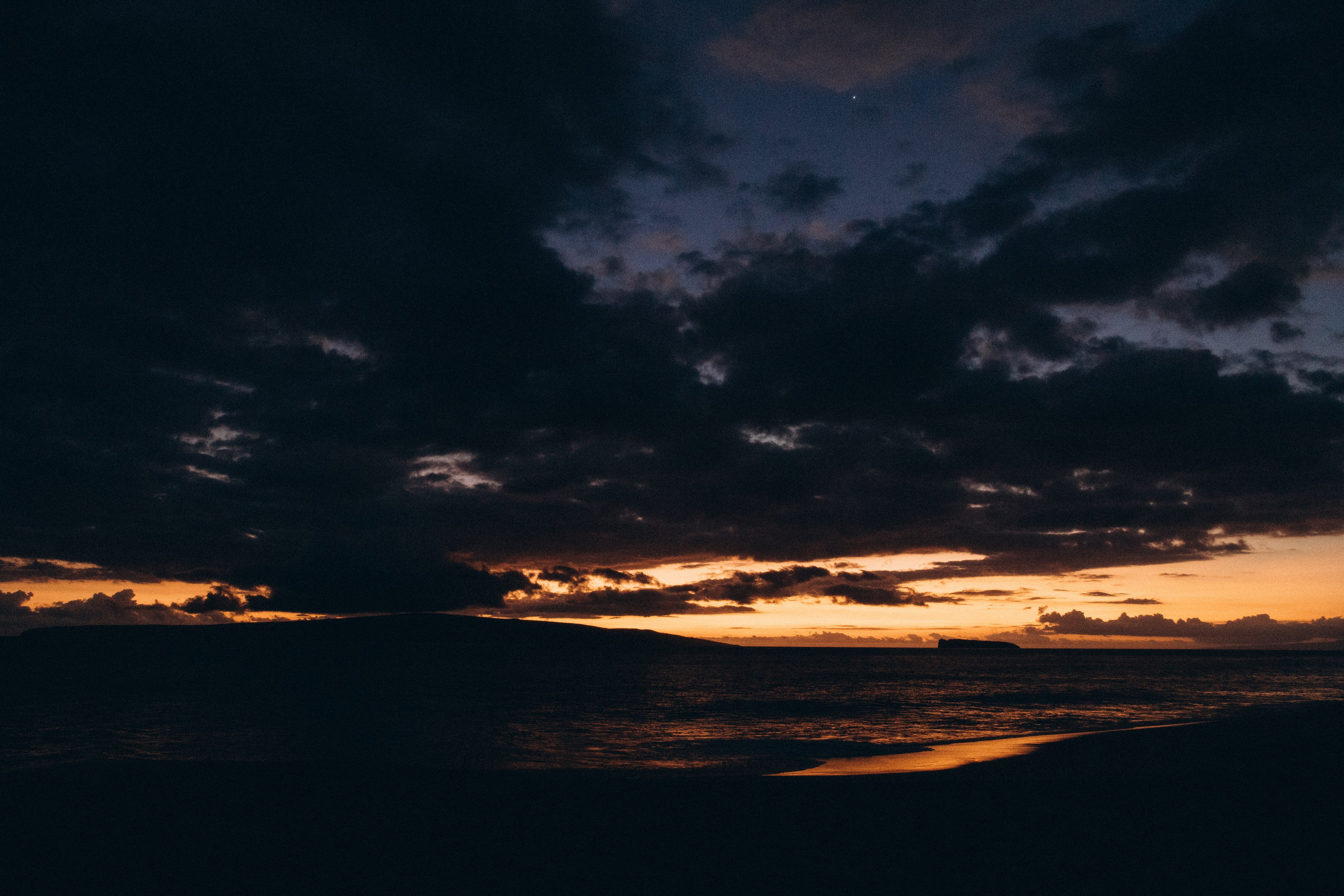 Stunning Maui sunset with dramatic clouds and island silhouette over the ocean