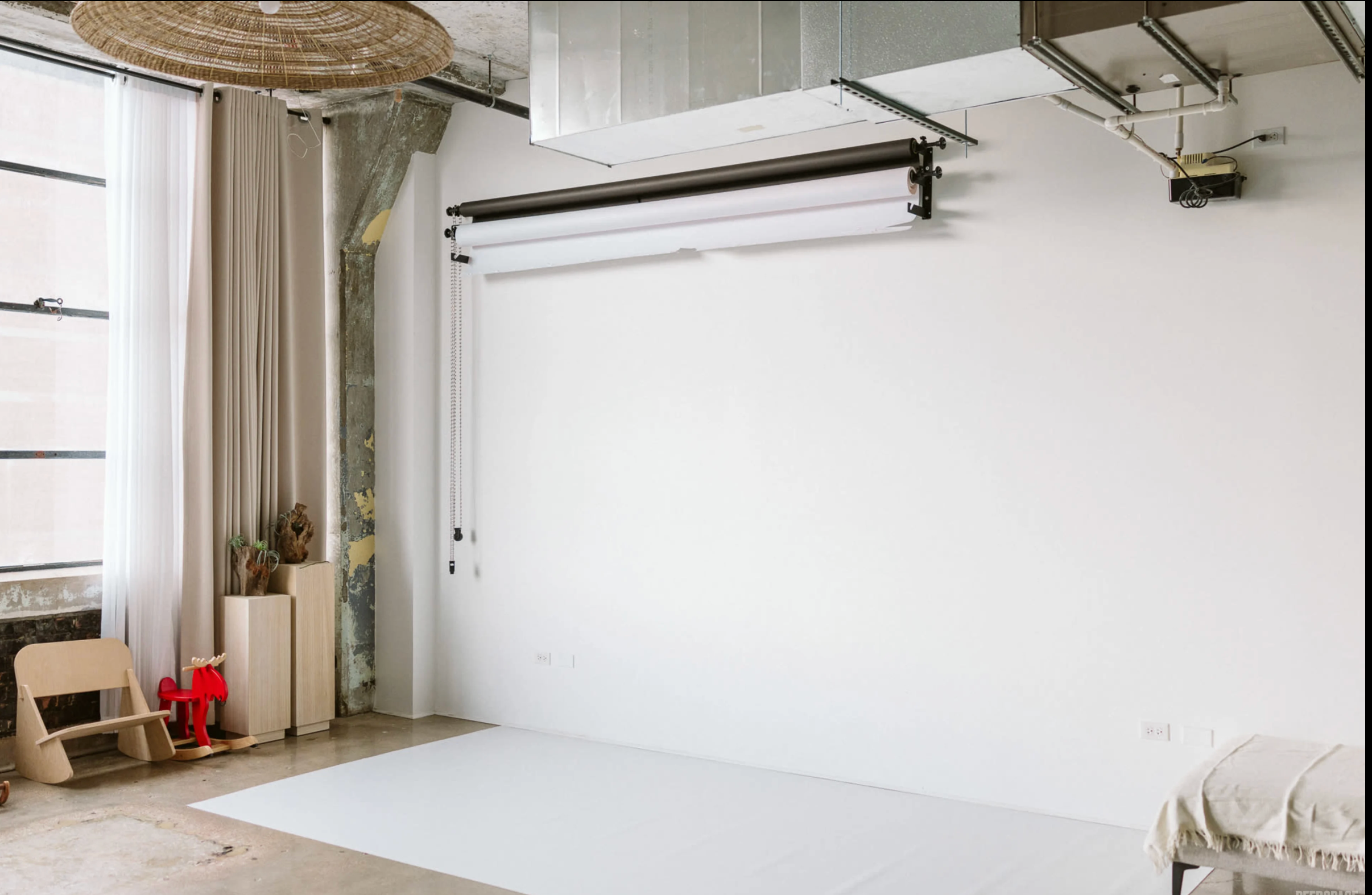 Natural light photography studio with neutral styling and floral decor