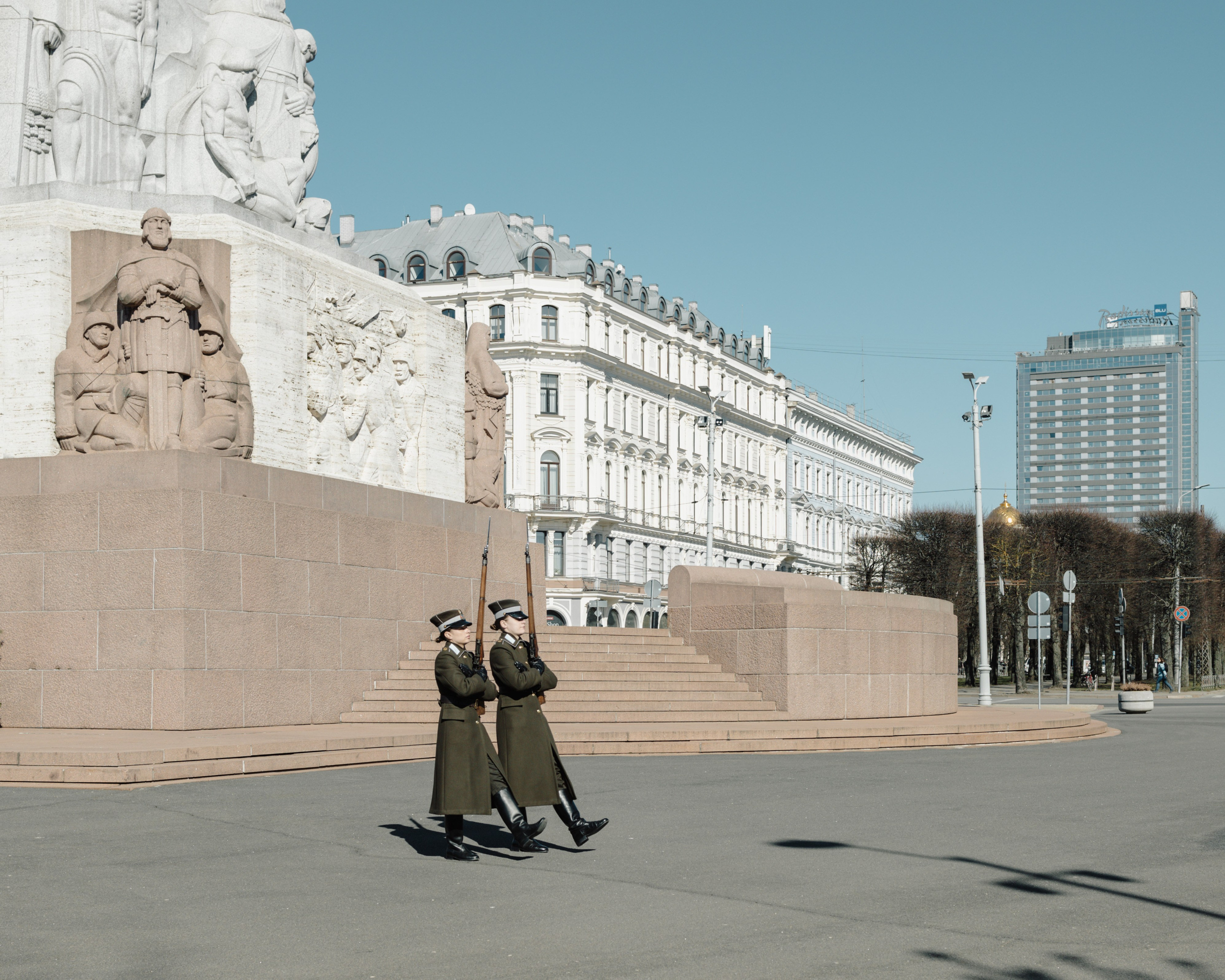 Two female soldiers walk past the Freedom Monument in central Riga during a shift change. The monument, honoring soldiers killed in the Latvian War of Independence, is guarded around the clock.
