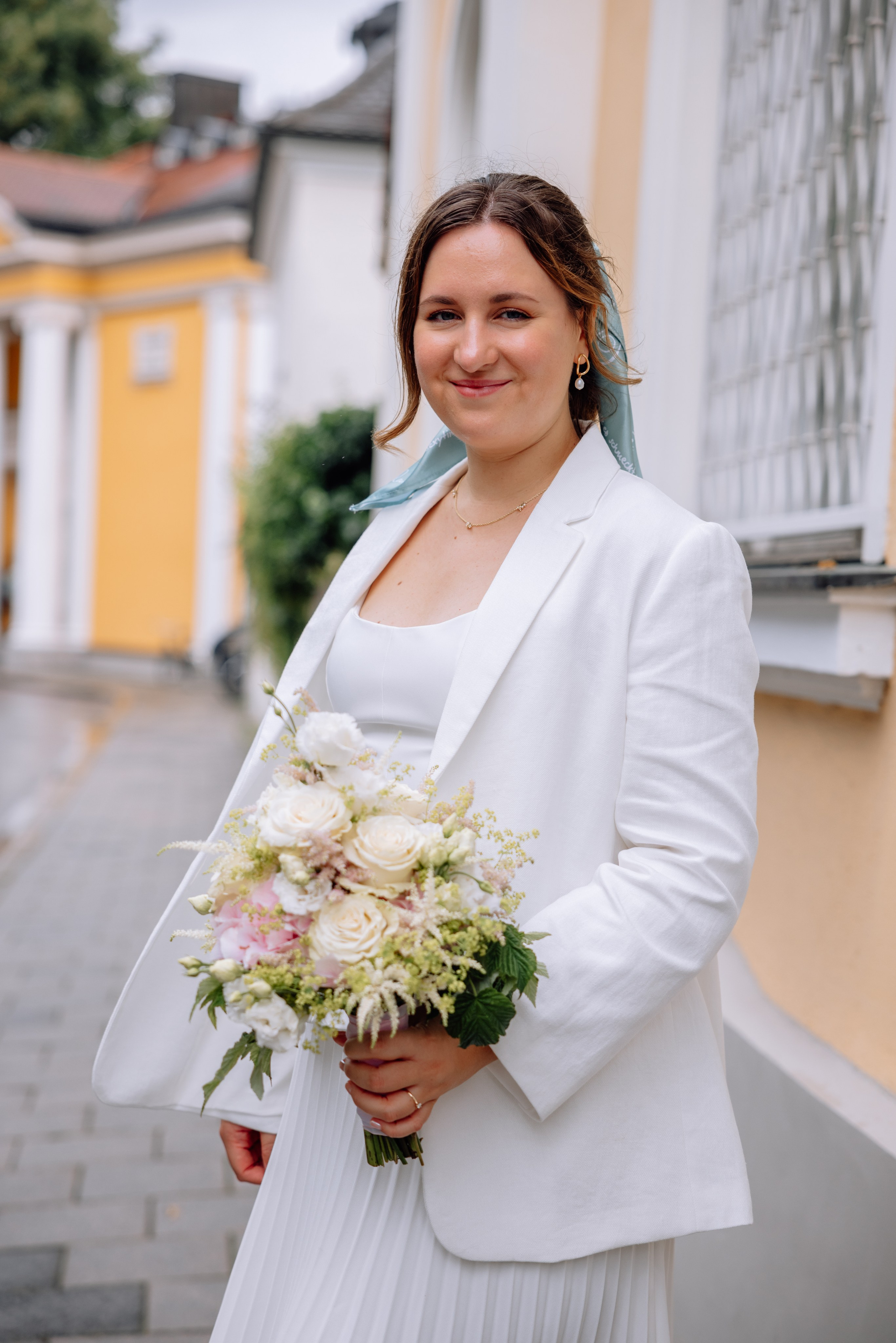 Braut hält Blumenstrauß – elegantes Hochzeitskleid im Fokus