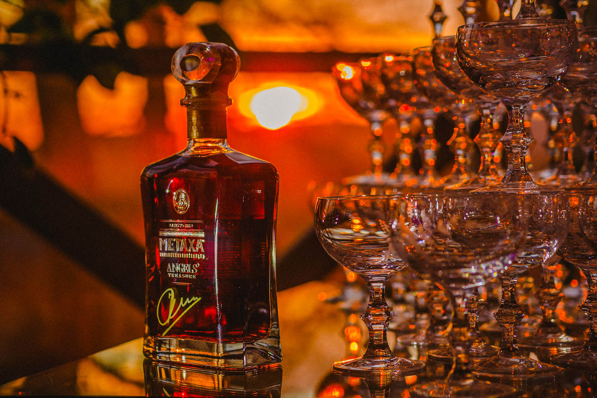A bottle is illuminated against the setting sun near a pyramid of glasses during a VIP private party at the Chateau Mcely in Prague.