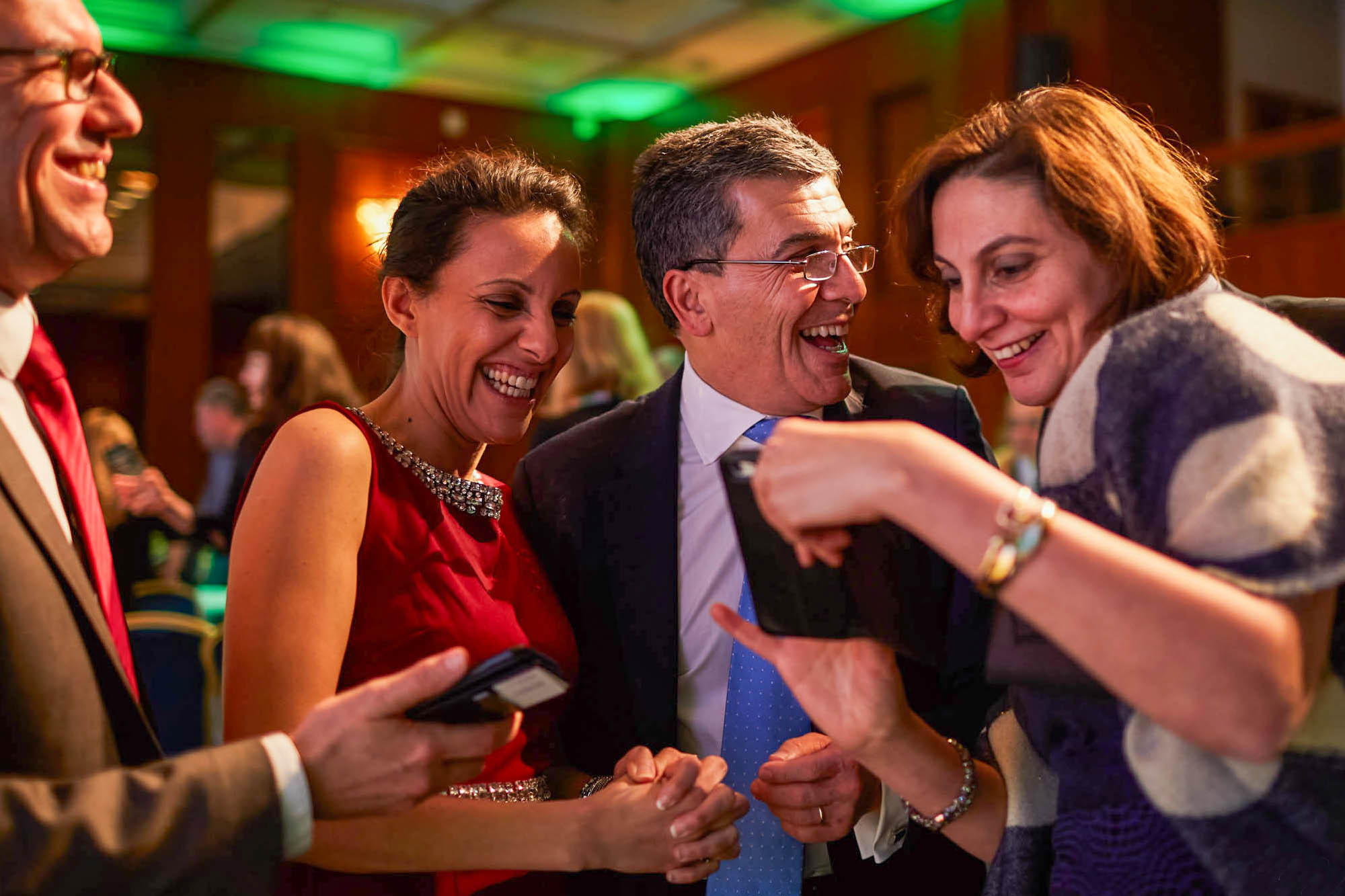 A feature photo showing several smiling men and woman enjoying looking at a polaroid captured of them during a gala event in Prague.