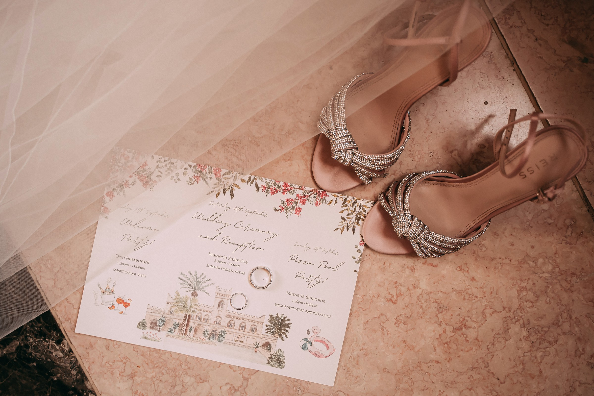 A detailed shot of a wedding invitation paired with sparkling bridal shoes, all placed on a stone floor at Masseria Salamina in Puglia, Italy.