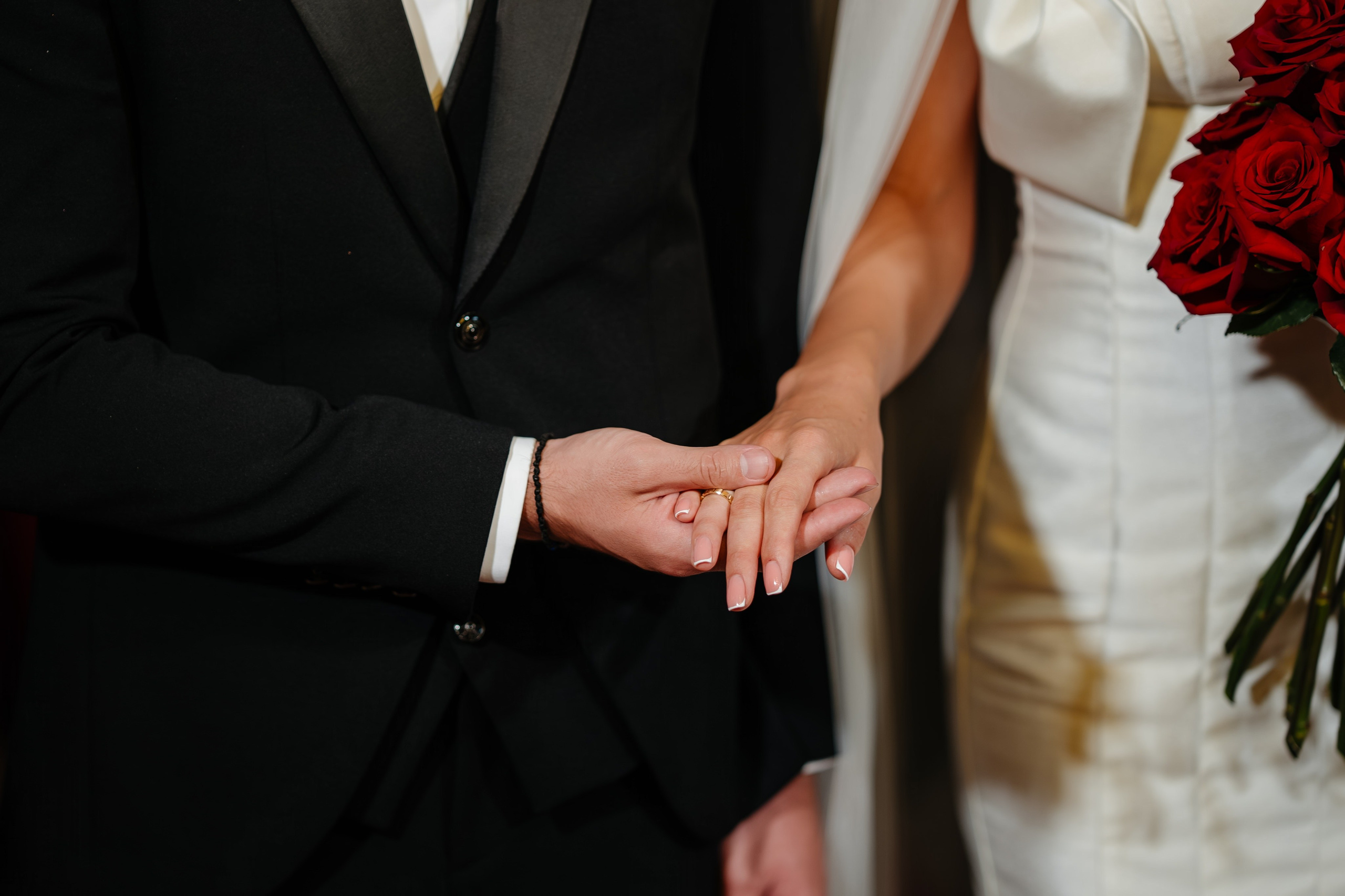 Detaliu emoționant cu schimbul verighetelor în fața preotului.