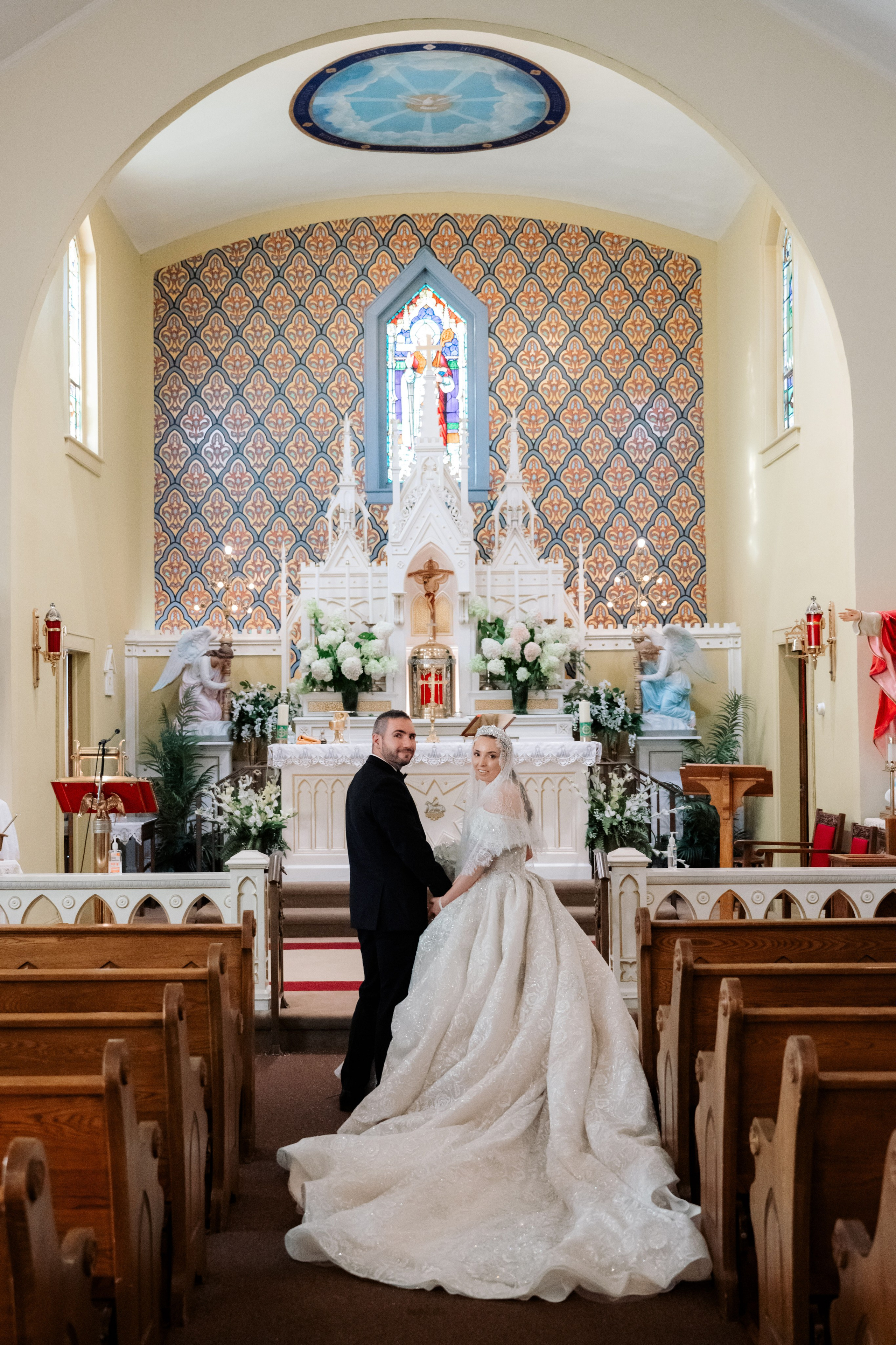 a bride and groom kneeling in front of a church altar
