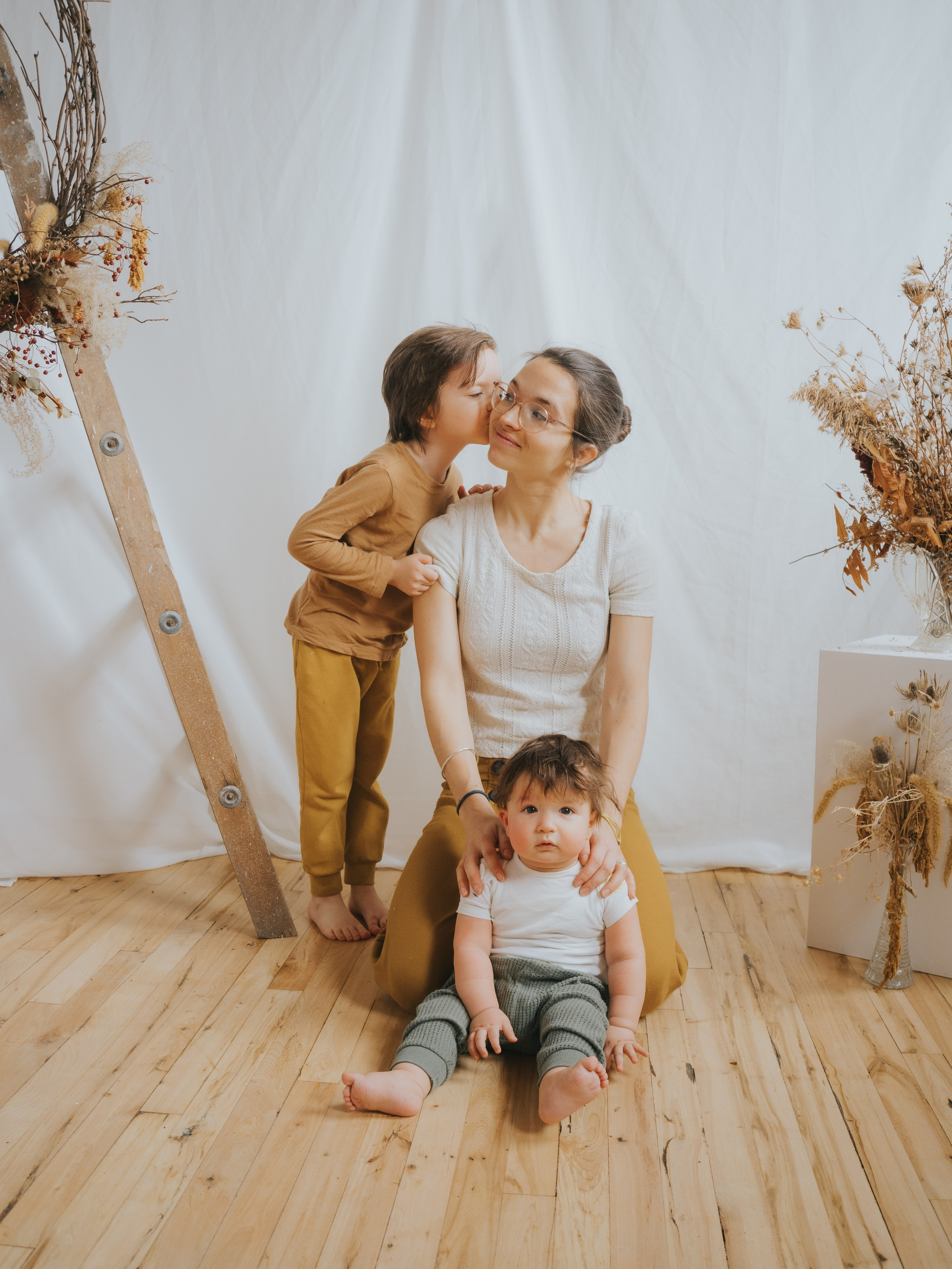 Older sibling giving mother kiss on cheek.