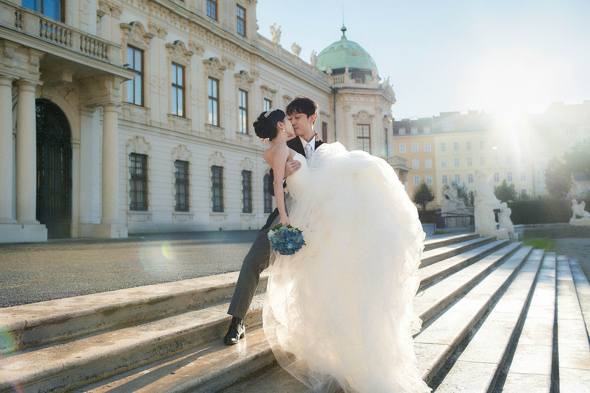 Groom carrying bride with sun flare in Belvedere gardens.