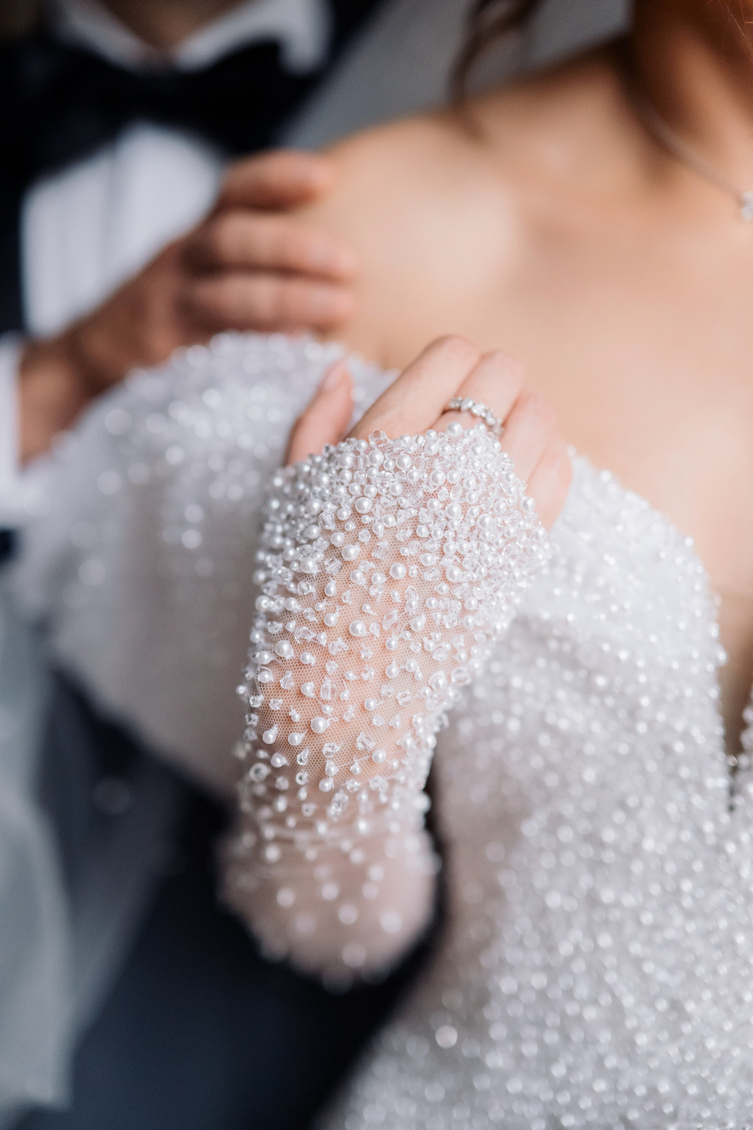 a bride holding a white wedding dress with pearls