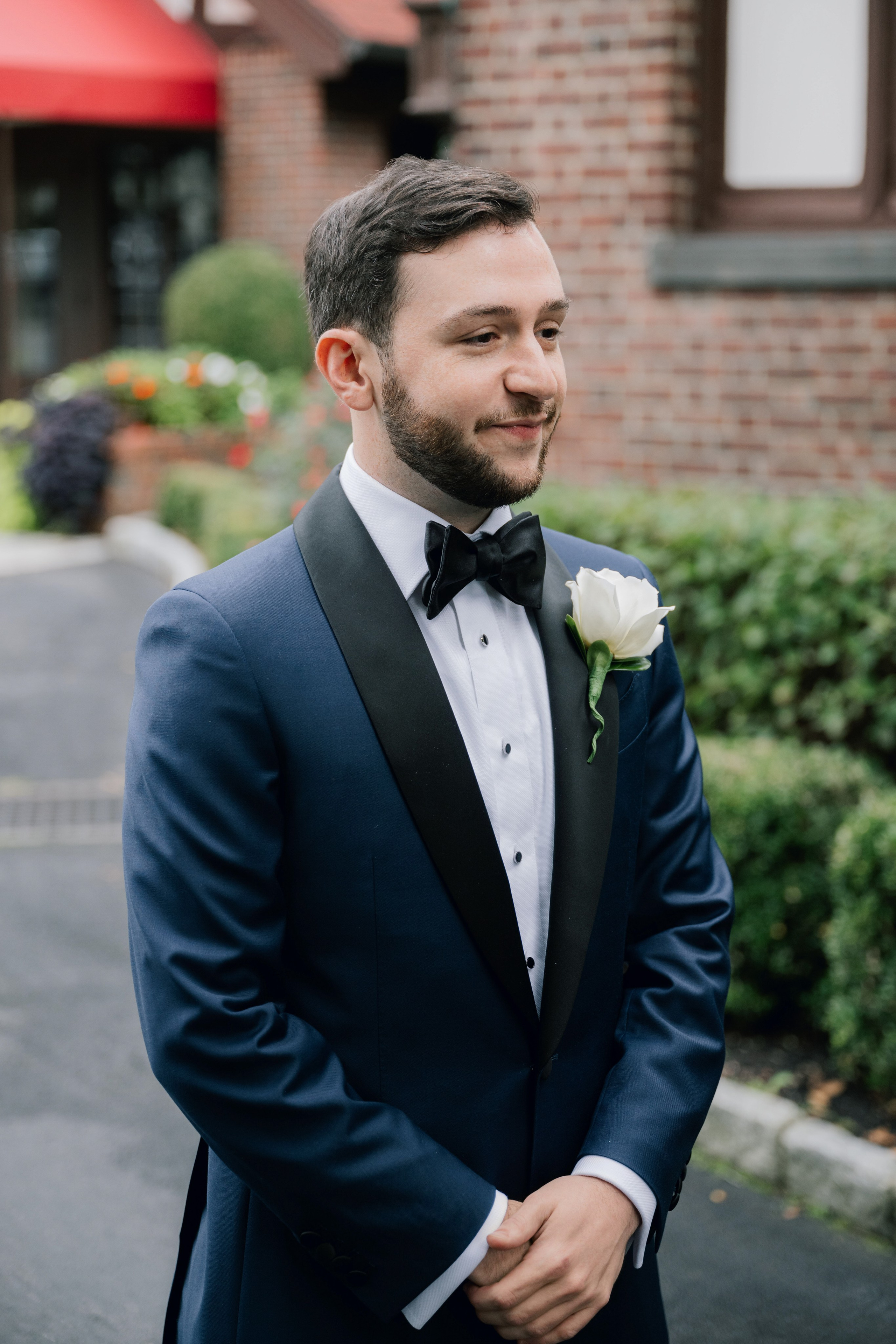a man in a suit and bow tie standing in front of a building