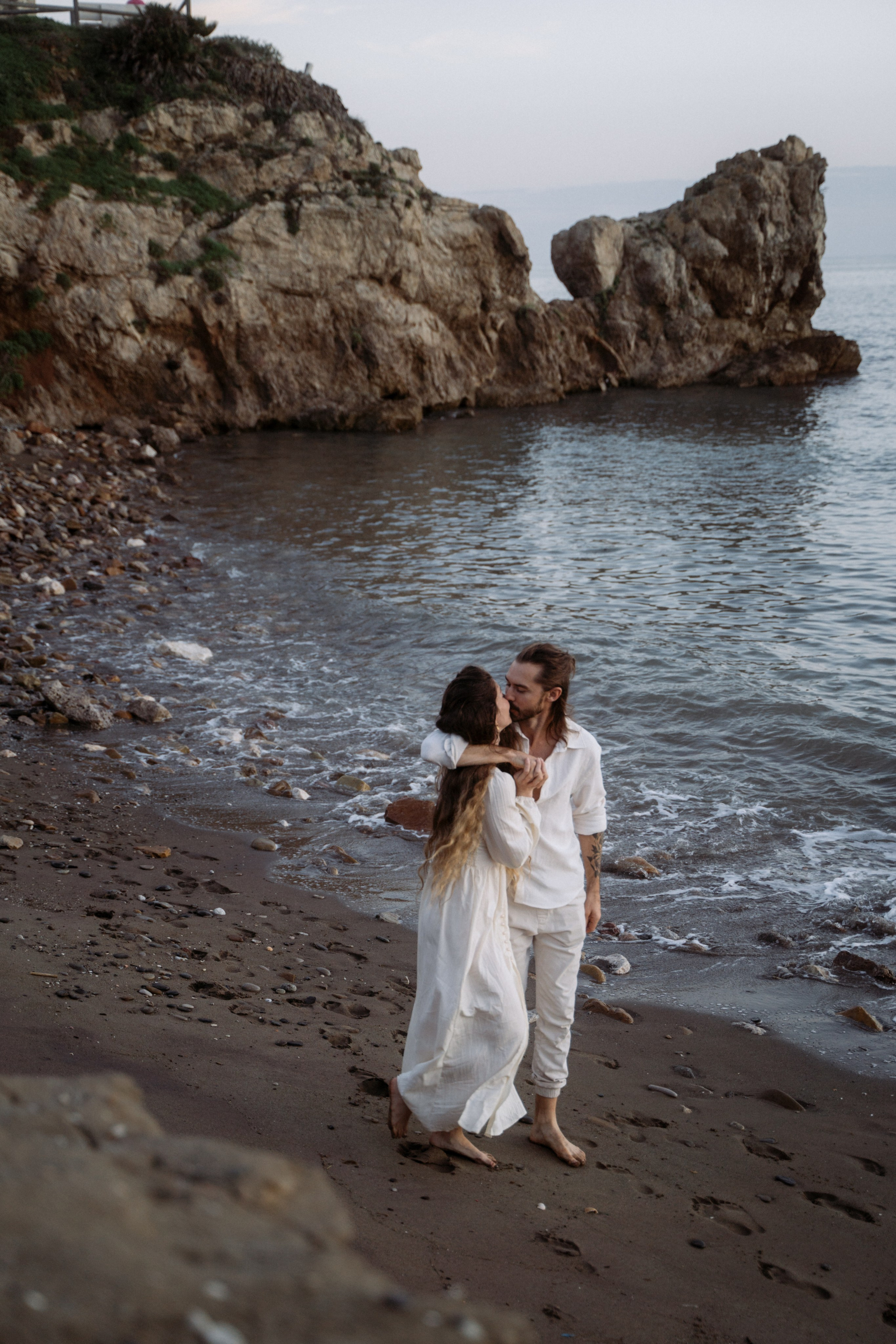 Couple embracing on the beach, surrounded by the beauty of the sea