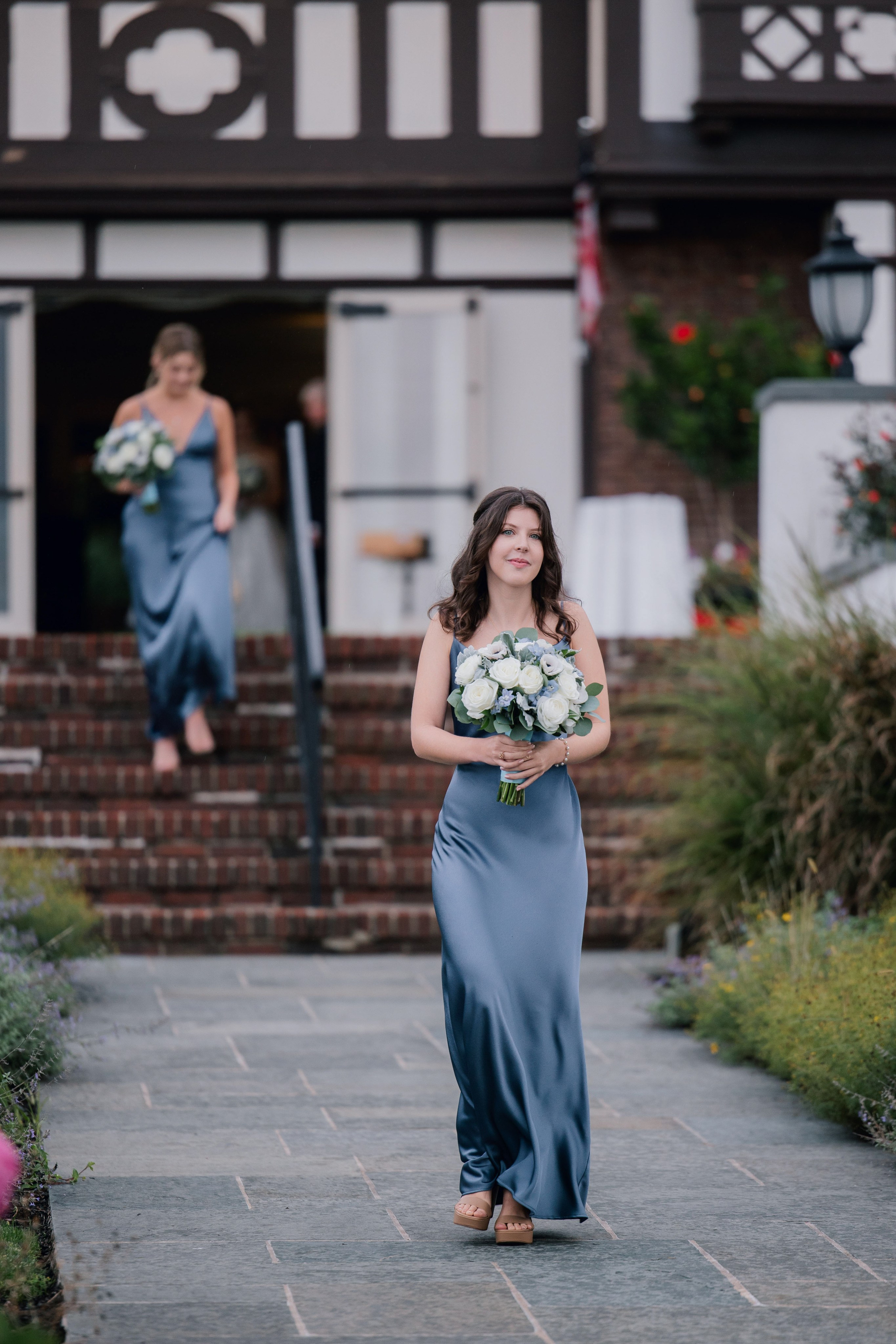 a woman in a blue dress walking down a sidewalk