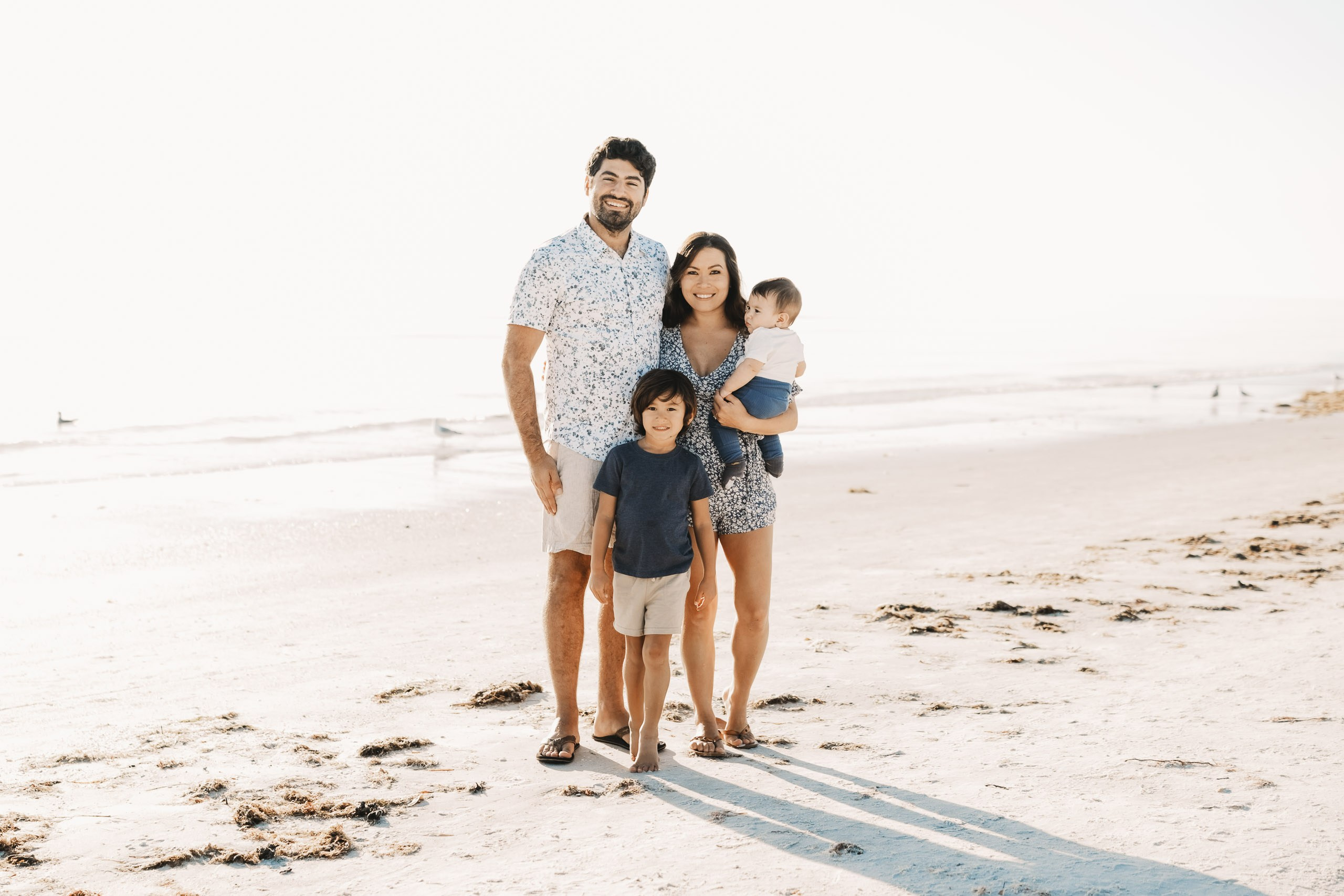 Family of four standing on the white sand of Siesta Key Beach during a sunset photo session in Sarasota.
