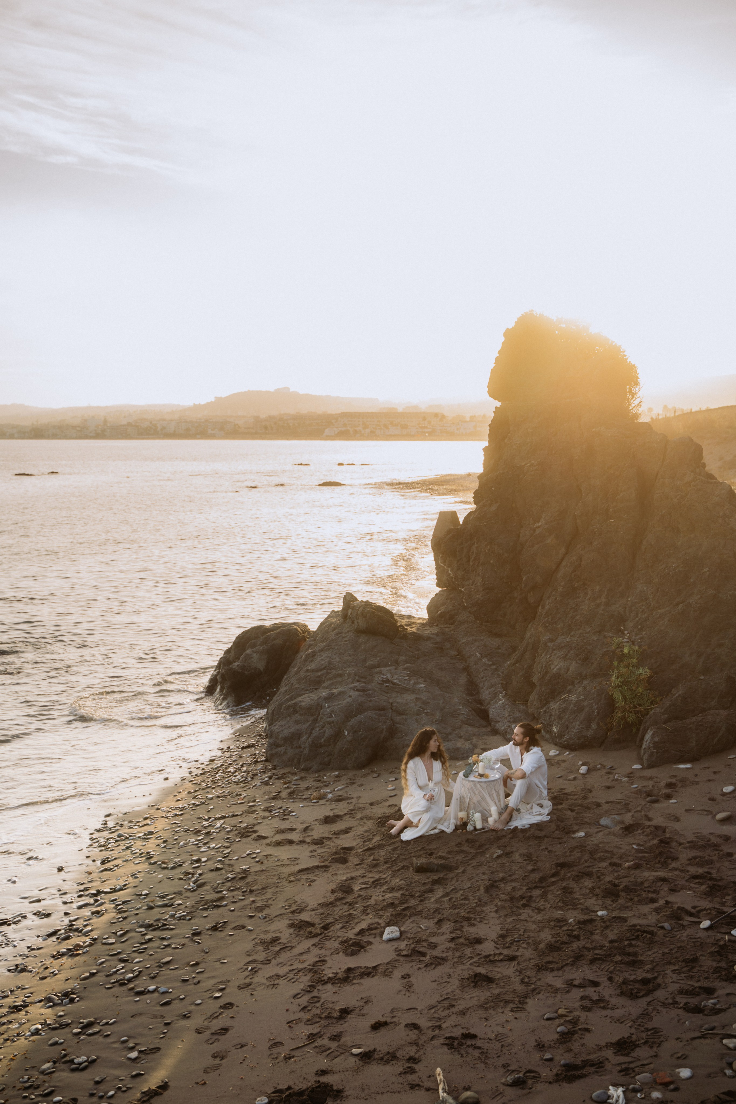 Couple enjoying a romantic picnic on the beach at sunset