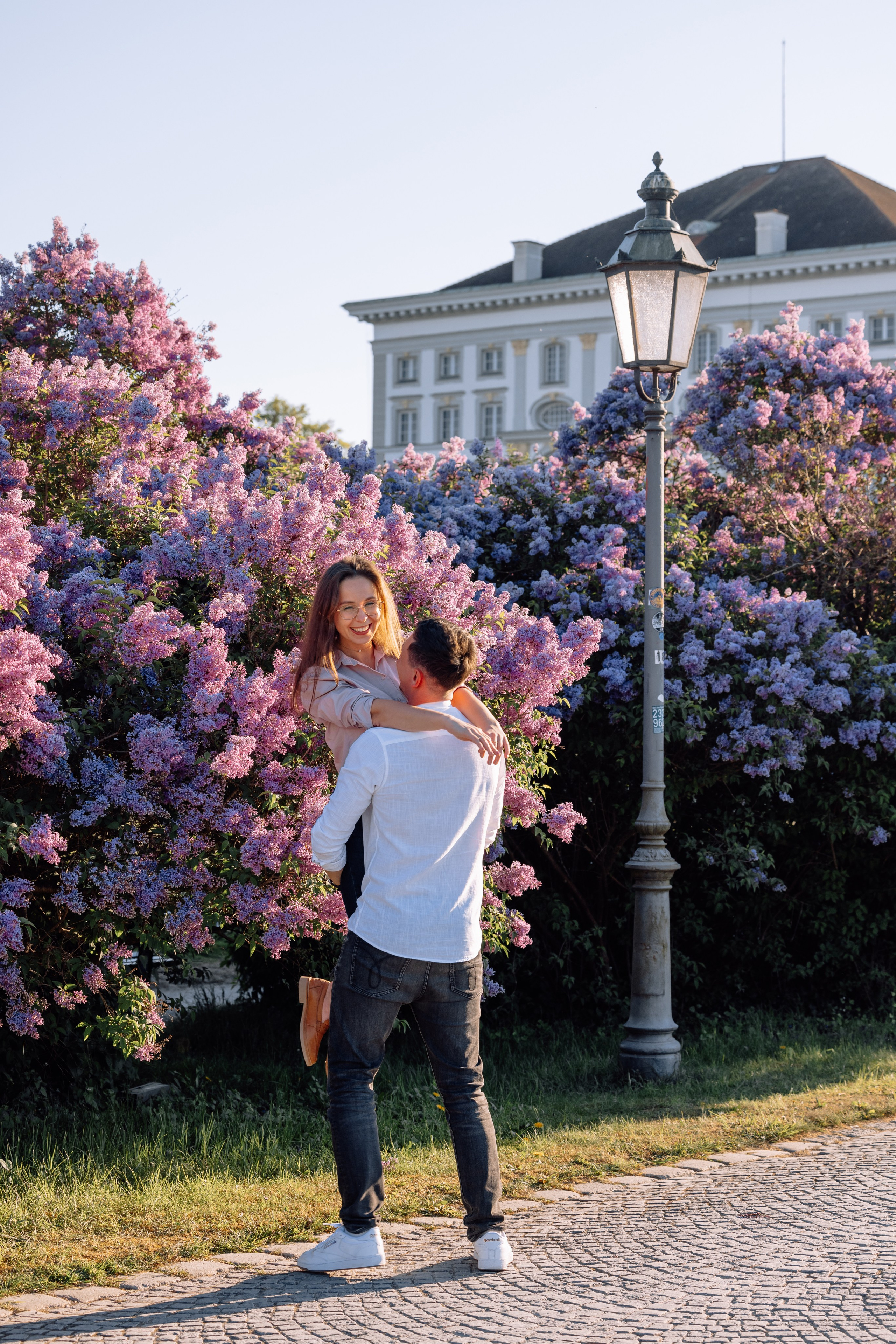 Papa hebt Mama auf die Arme und dreht sie lachend im Schlosspark Nymphenburg
