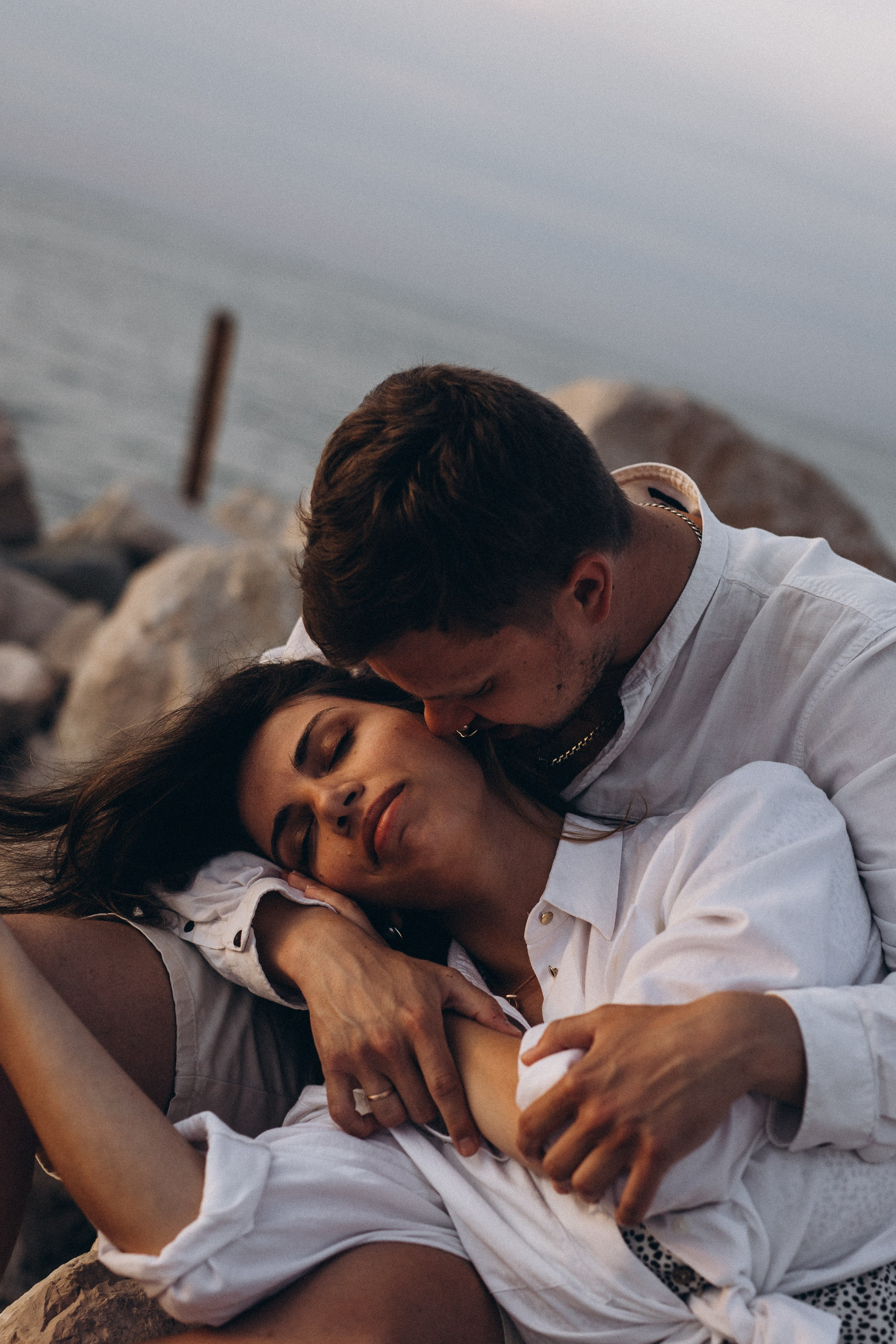 Donna incinta e il suo compagno abbracciati al mare in un momento di quiete