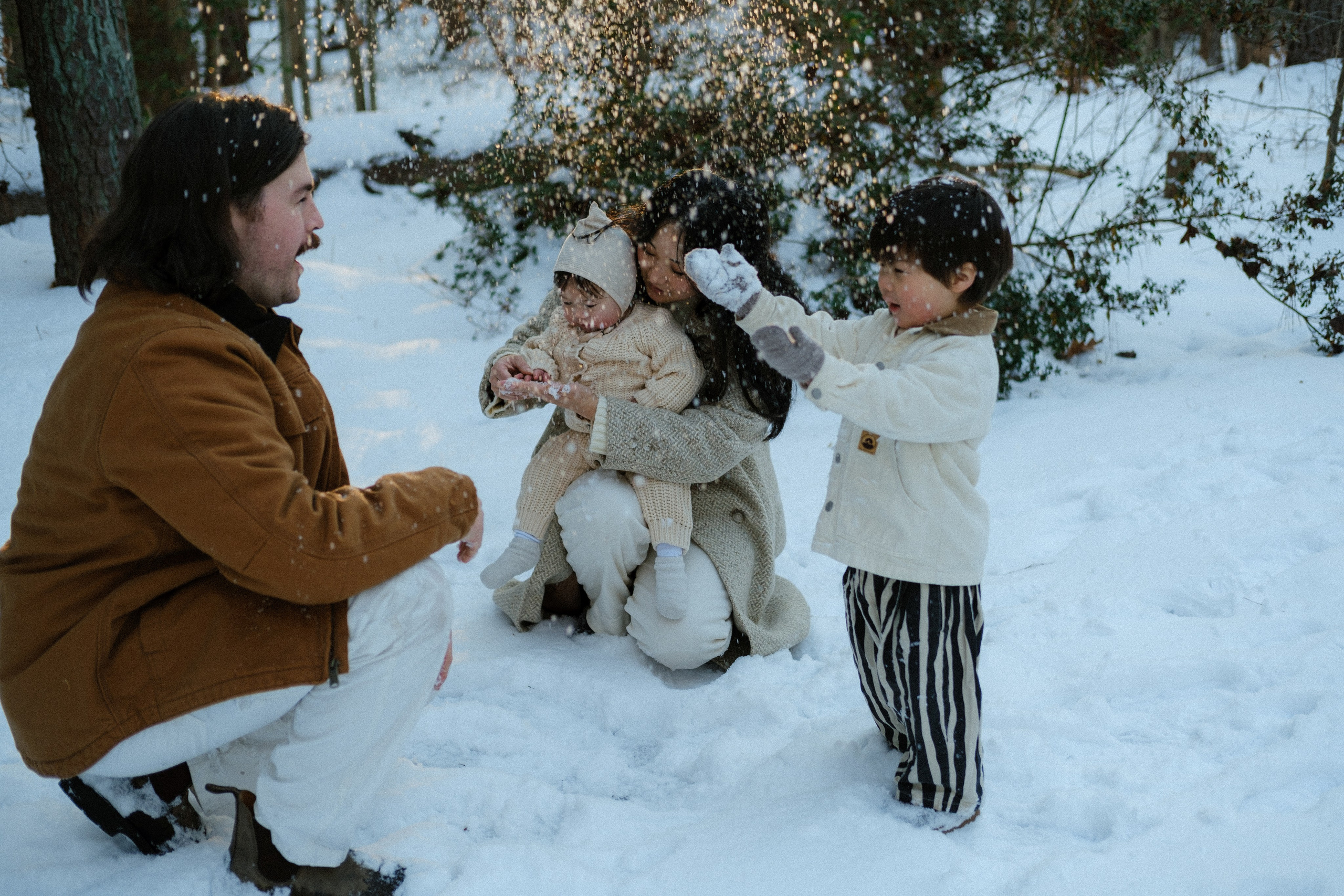 Mom and dad watching their kids play in the snow near Richmond, VA — simple family connection on a cold, beautiful day.