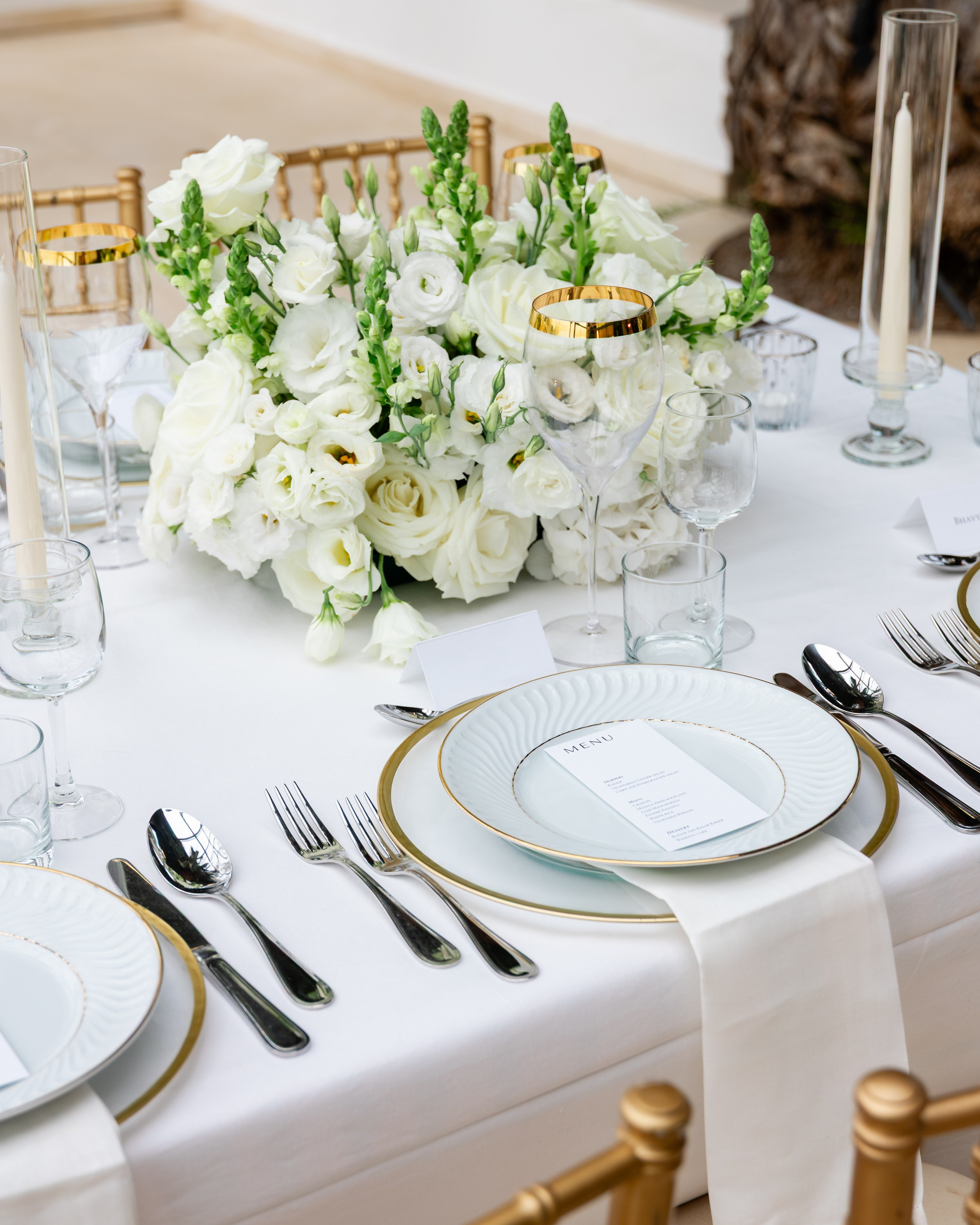 Elegant place setting with white floral centerpiece on a white tablecloth