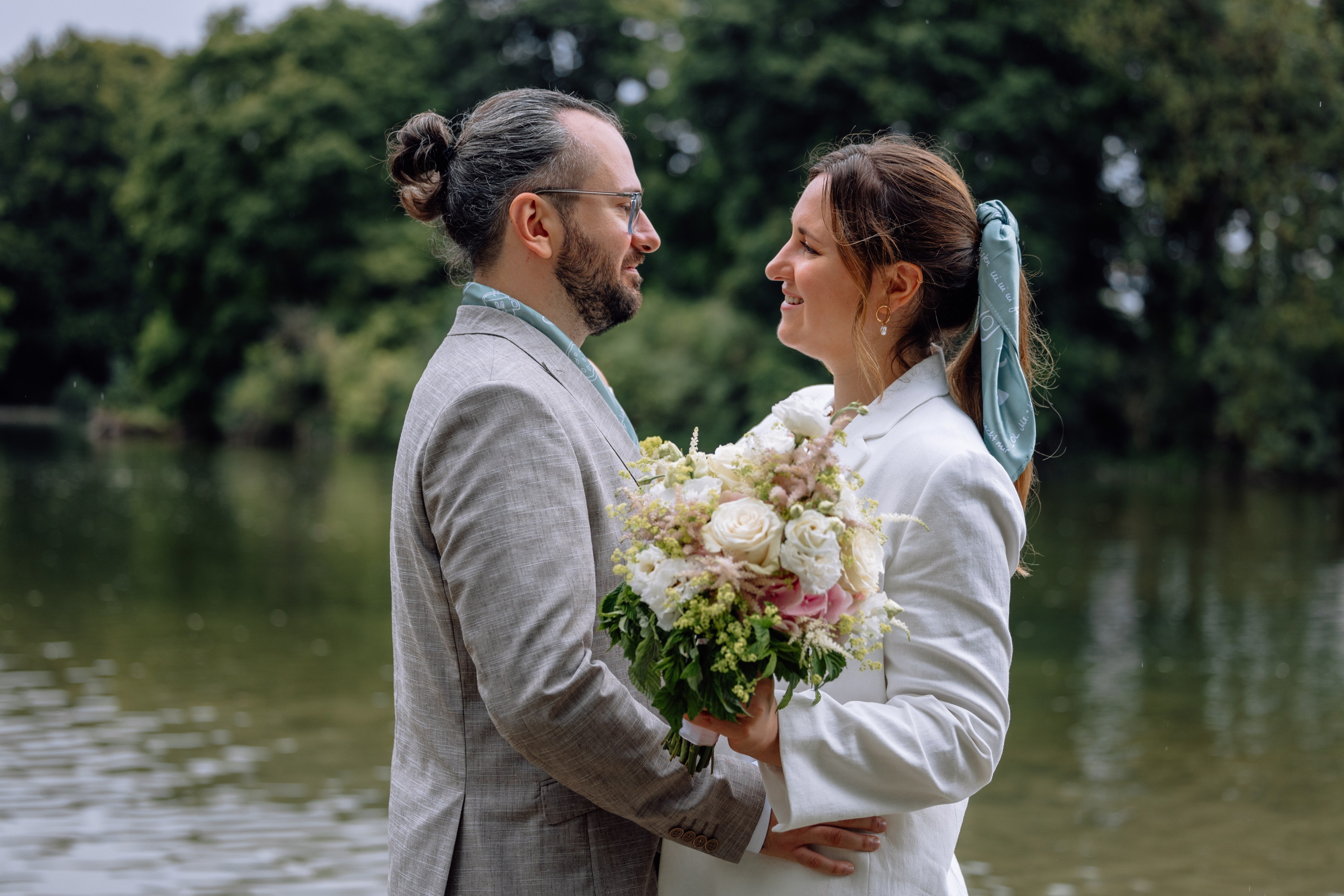 Brautpaar am kleinen Bach neben Standesamt Schwabing – hält sich umarmend, Blickkontakt