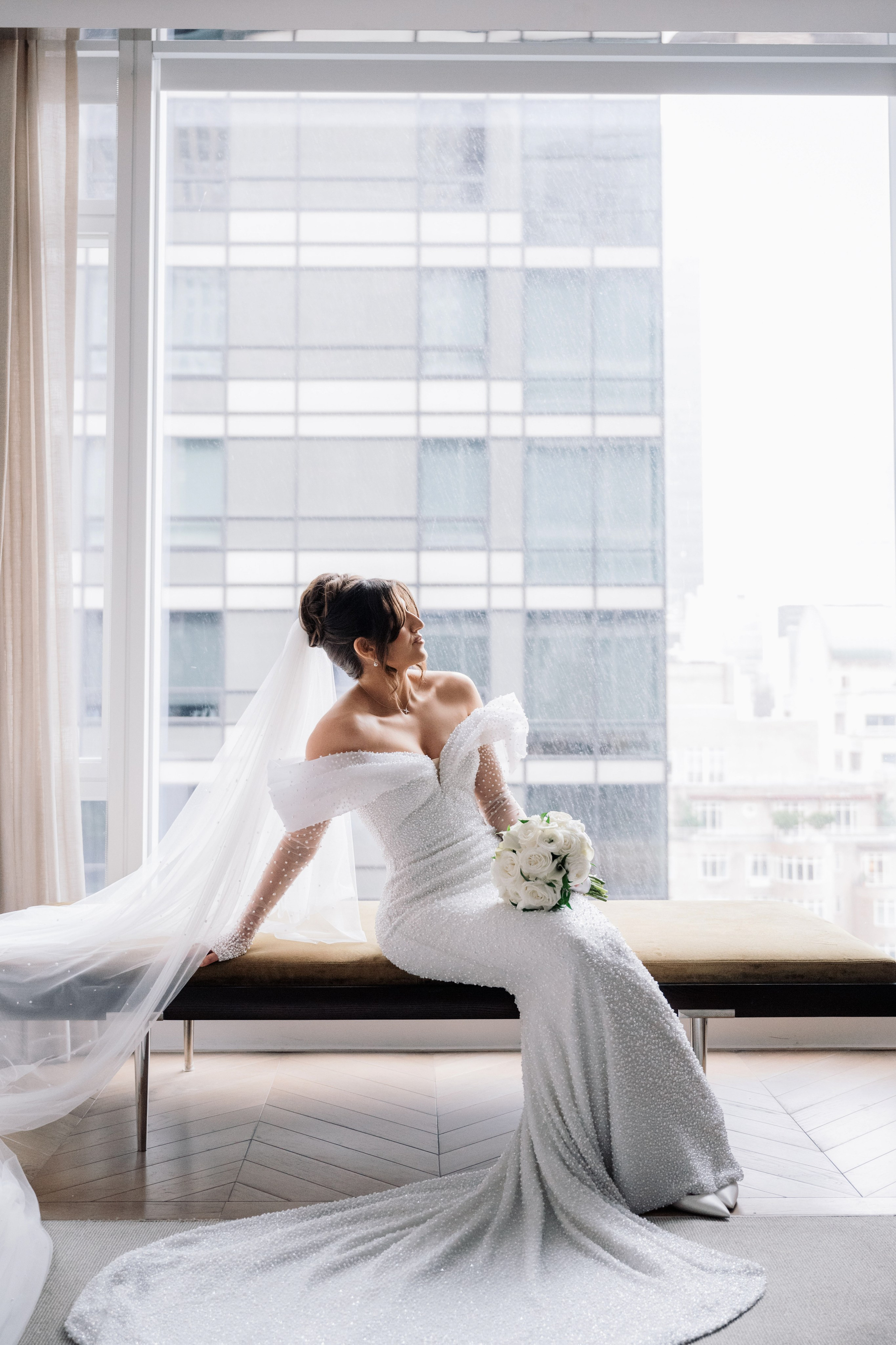 a bride sitting on a bench in front of a window