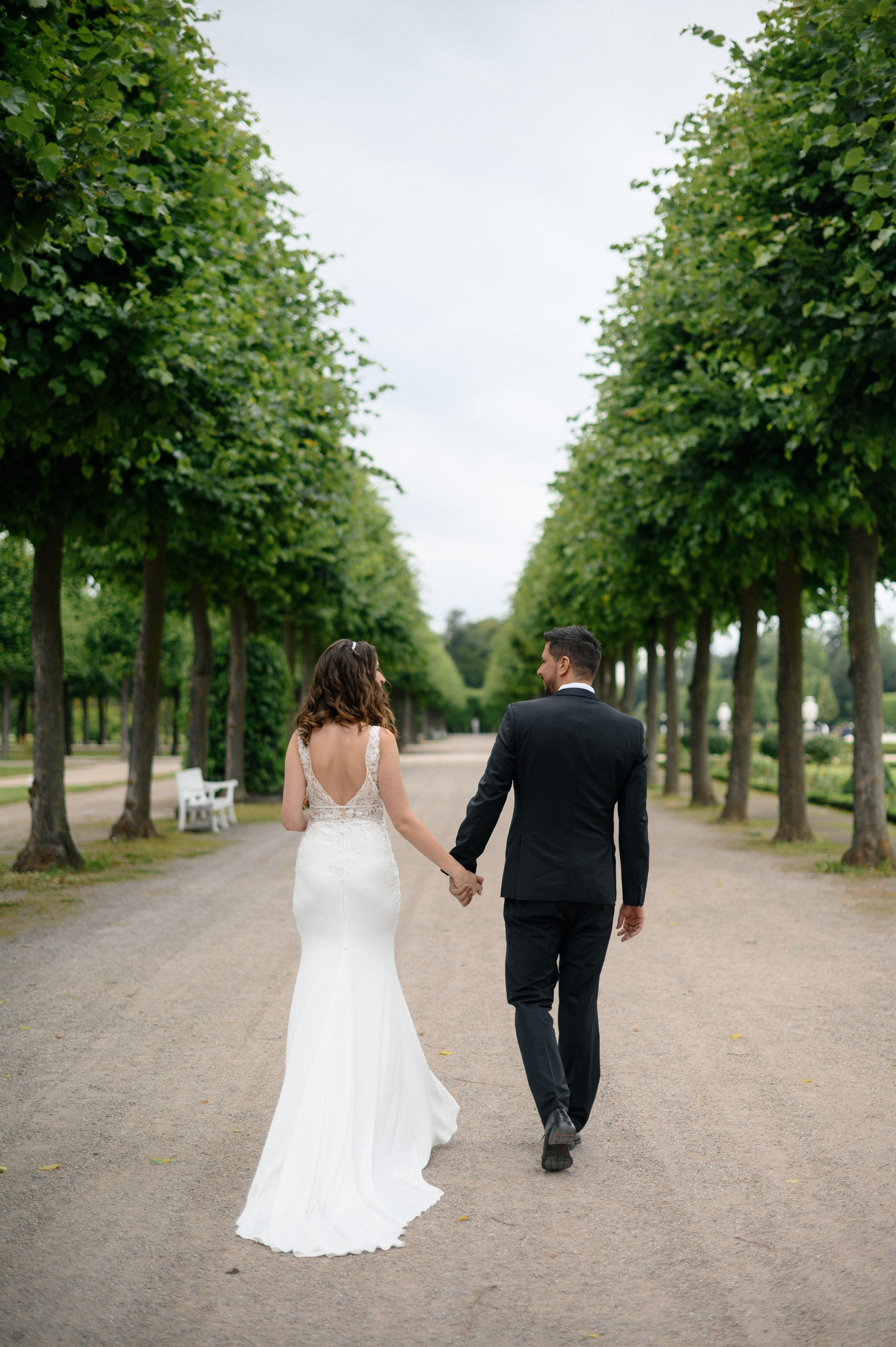 Brautpaar läuft Hand in Hand durch den Schlosspark