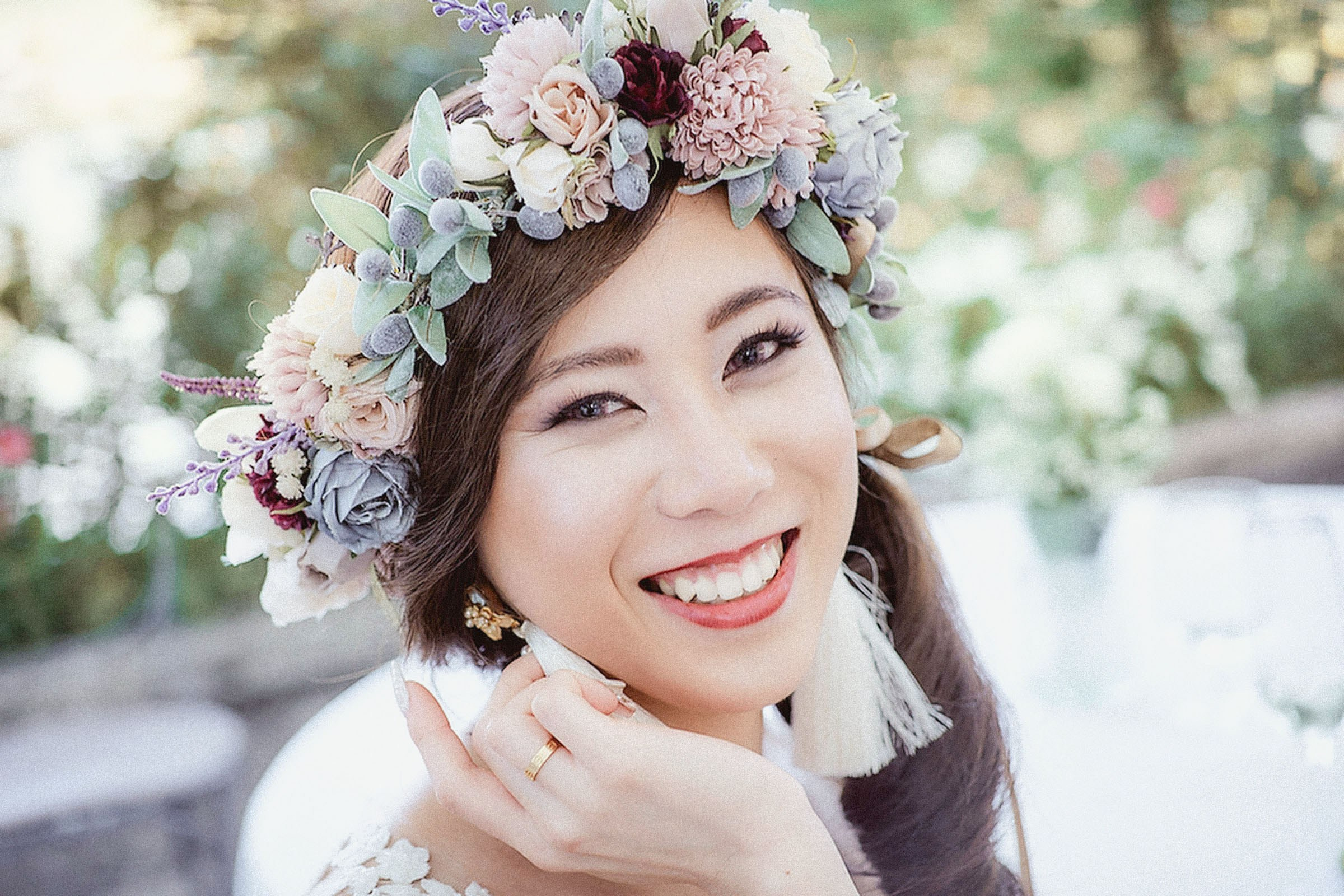 A Japanese bride, wearing a floral headpiece, smiles happily into the camera during her bridal portrait session.