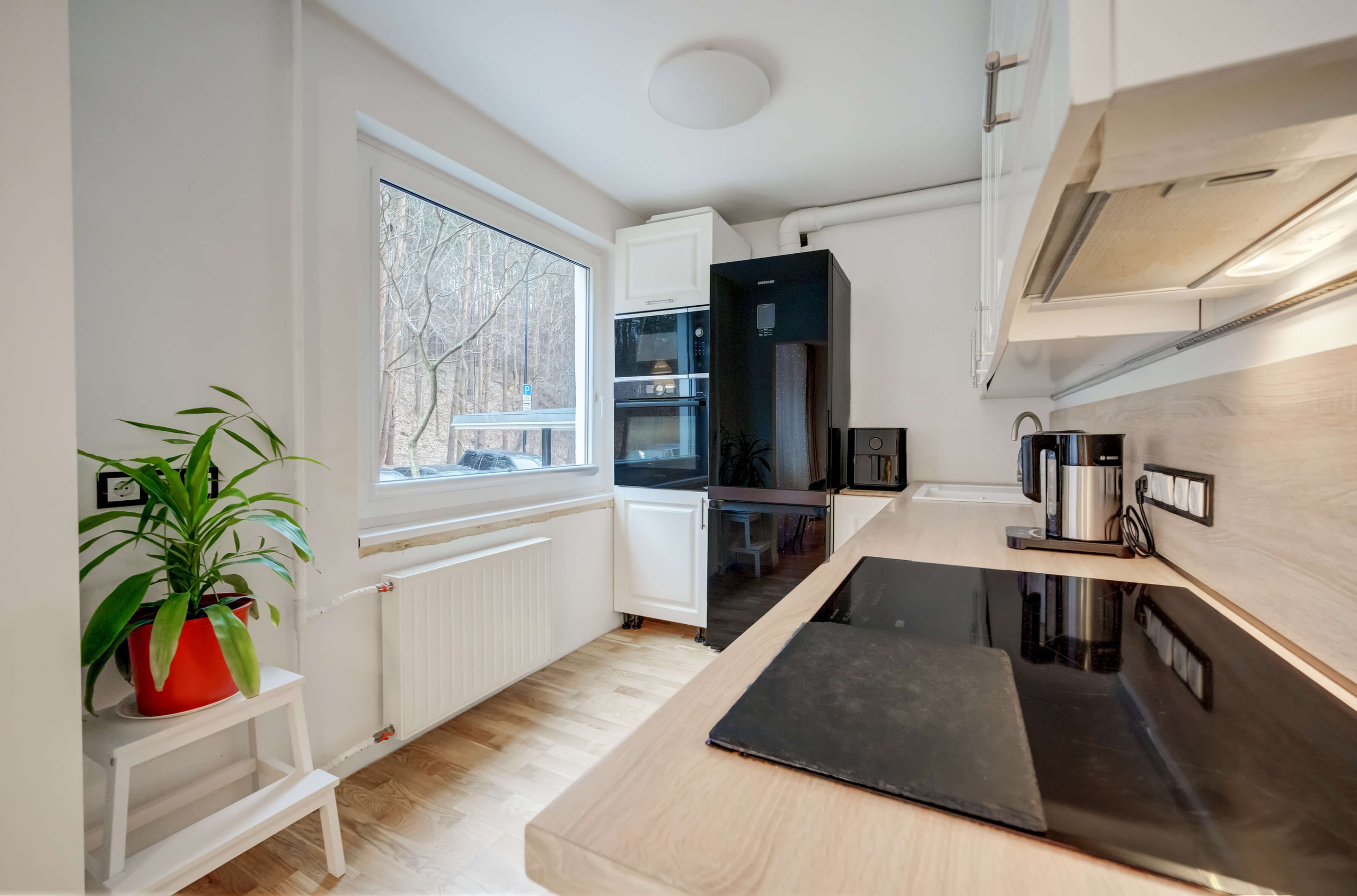 Erdvi svetainė-kitchen: šviesios spalvos, funkcionalūs baldai ir vaizdas, nuo kurio sunku atitraukti akis.