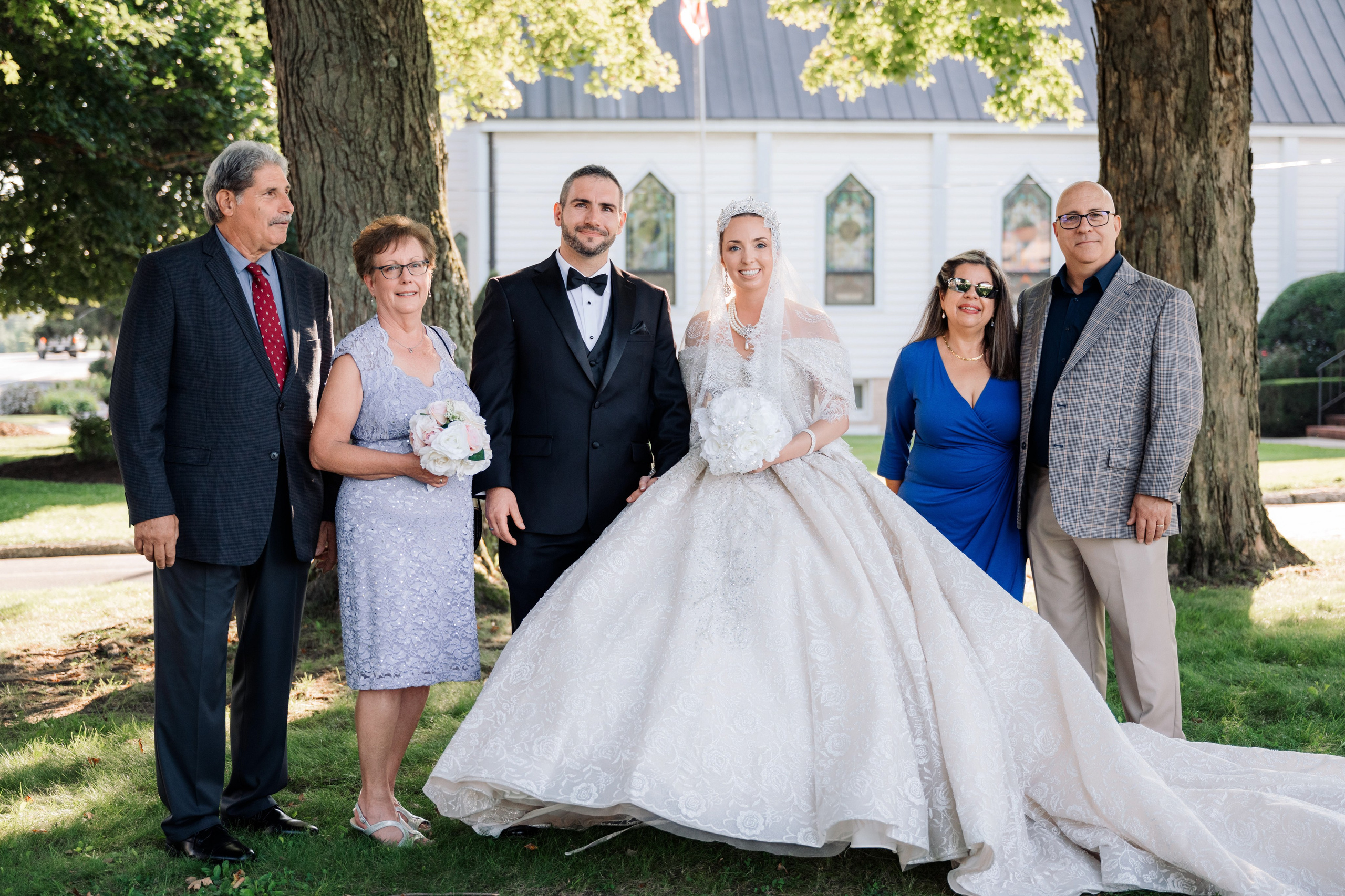 a bride and groom pose with their family