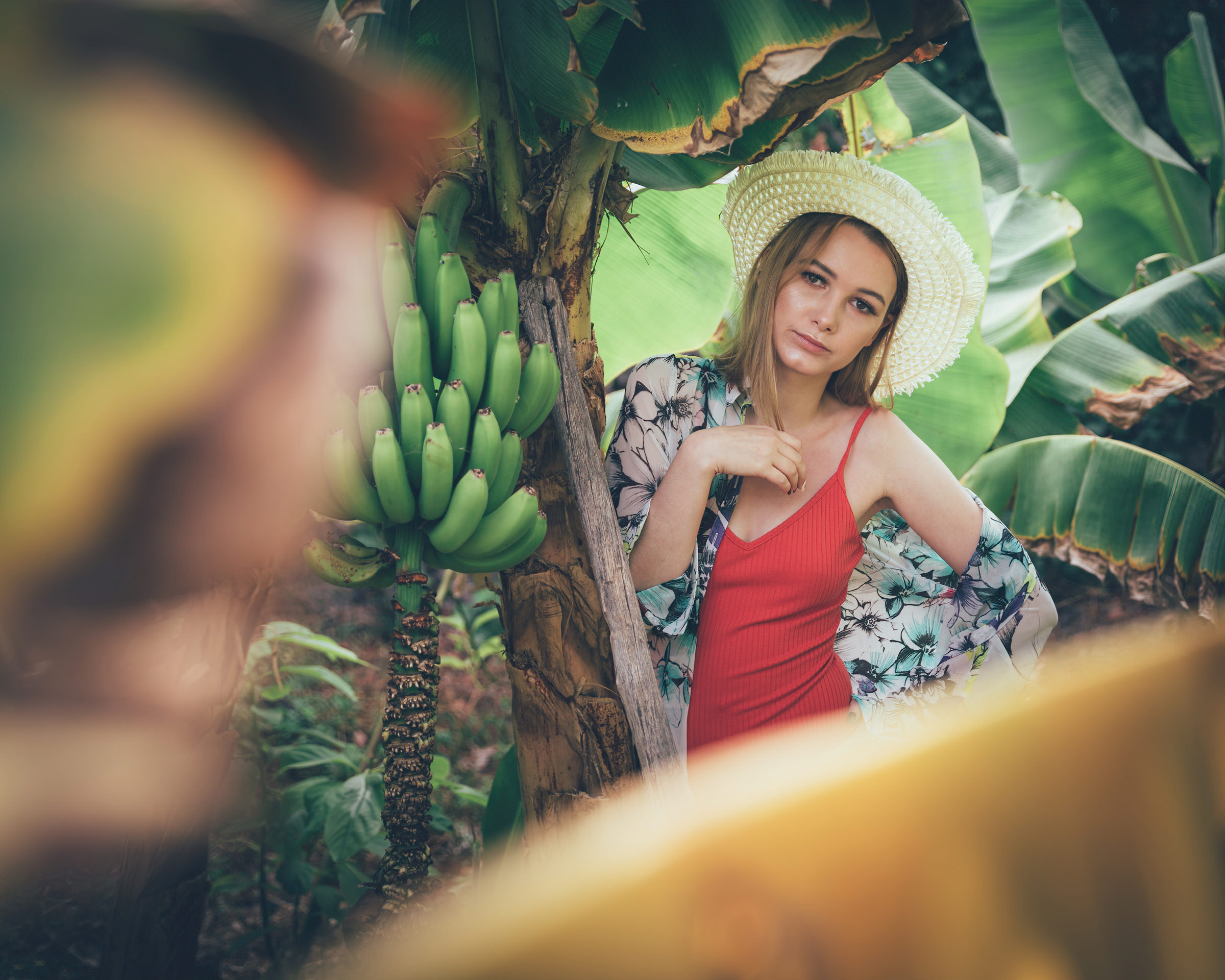 A woman in a red dress is standing in a banana plantation.