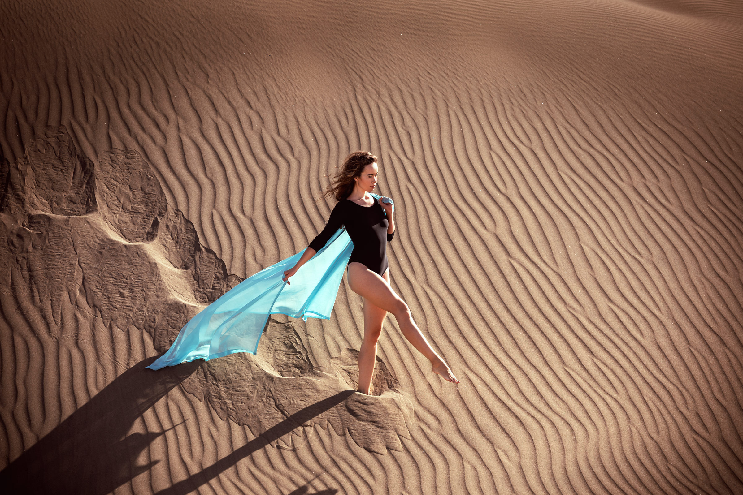 Photographer captures woman in blue cape against desert backdrop in Maspalomas.