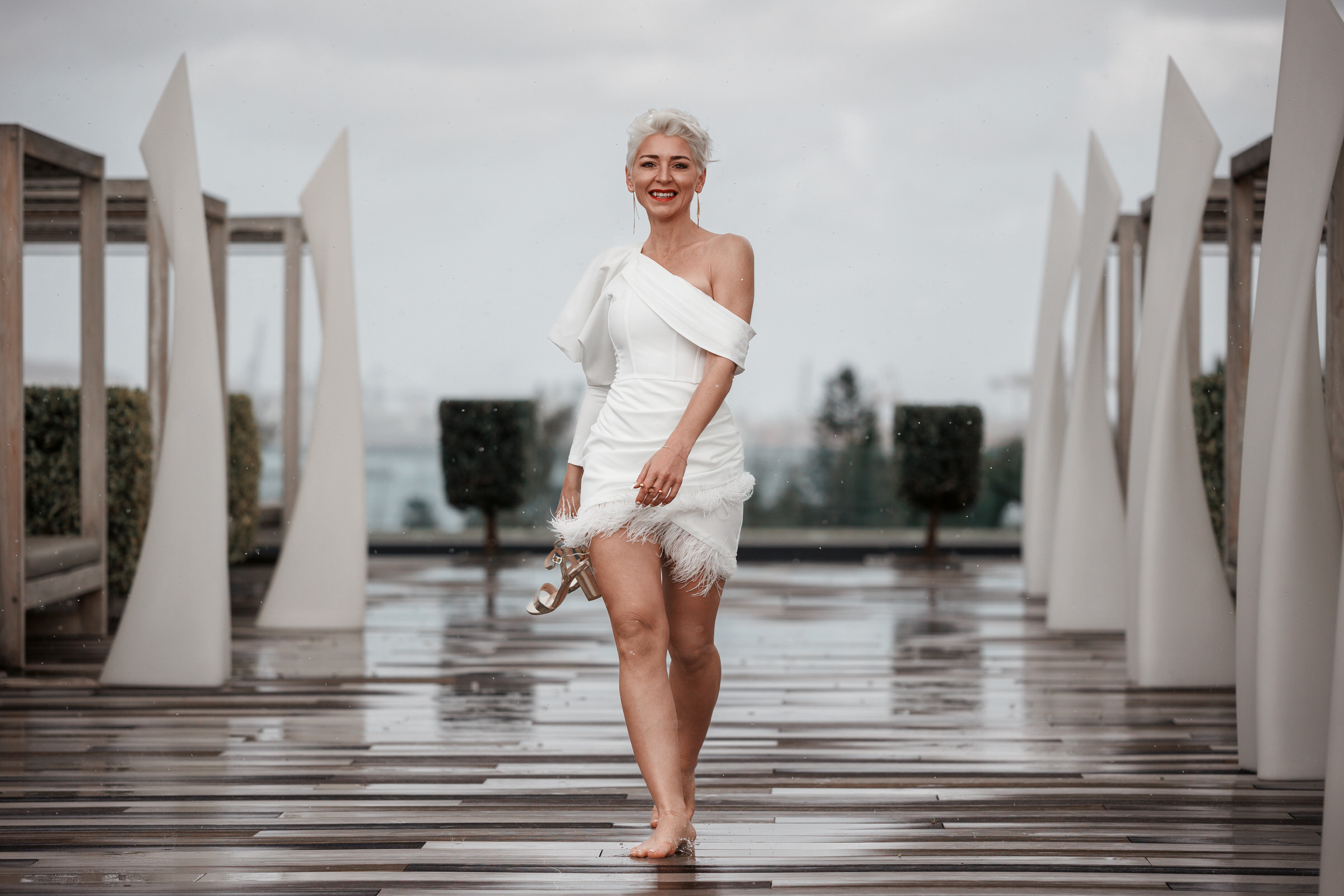 Elegant woman in white dress strolling on walkway at Hotel Santa Cantalina during photography session.