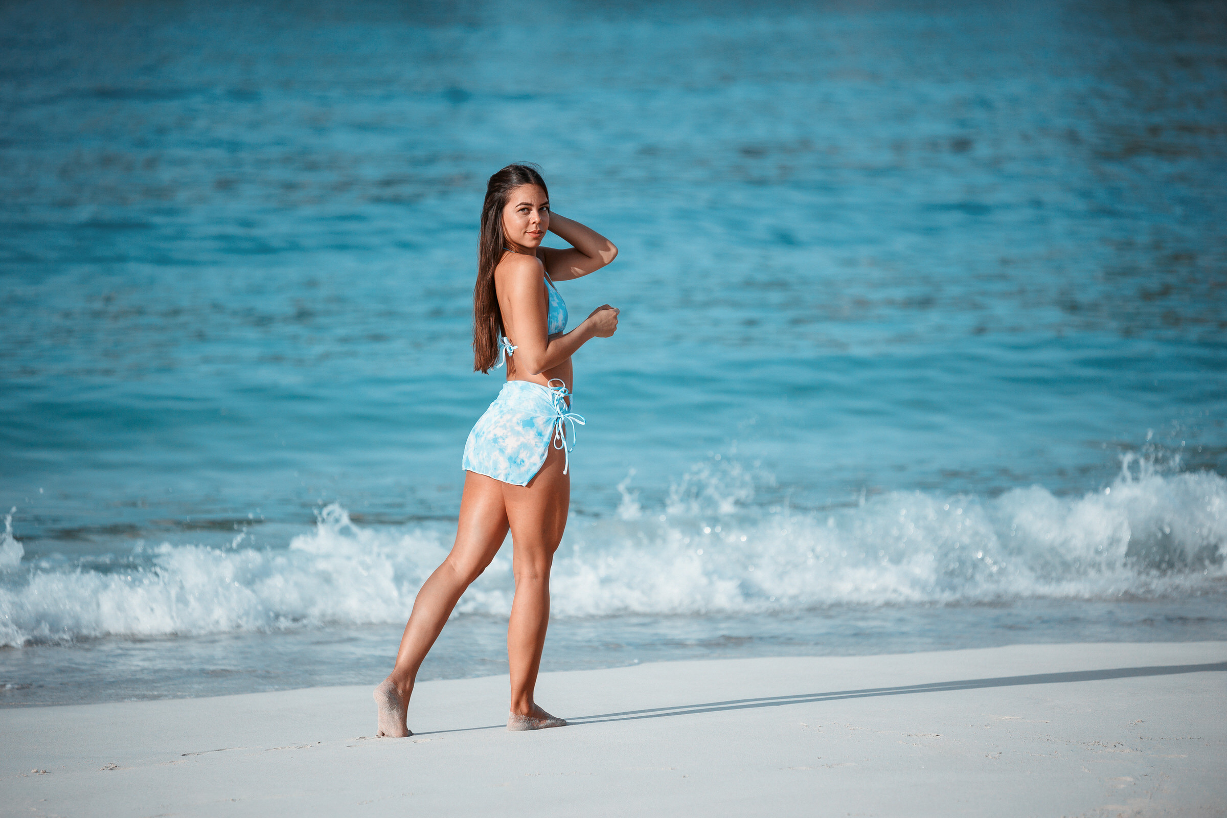 A woman in a blue bikini standing on the beach.