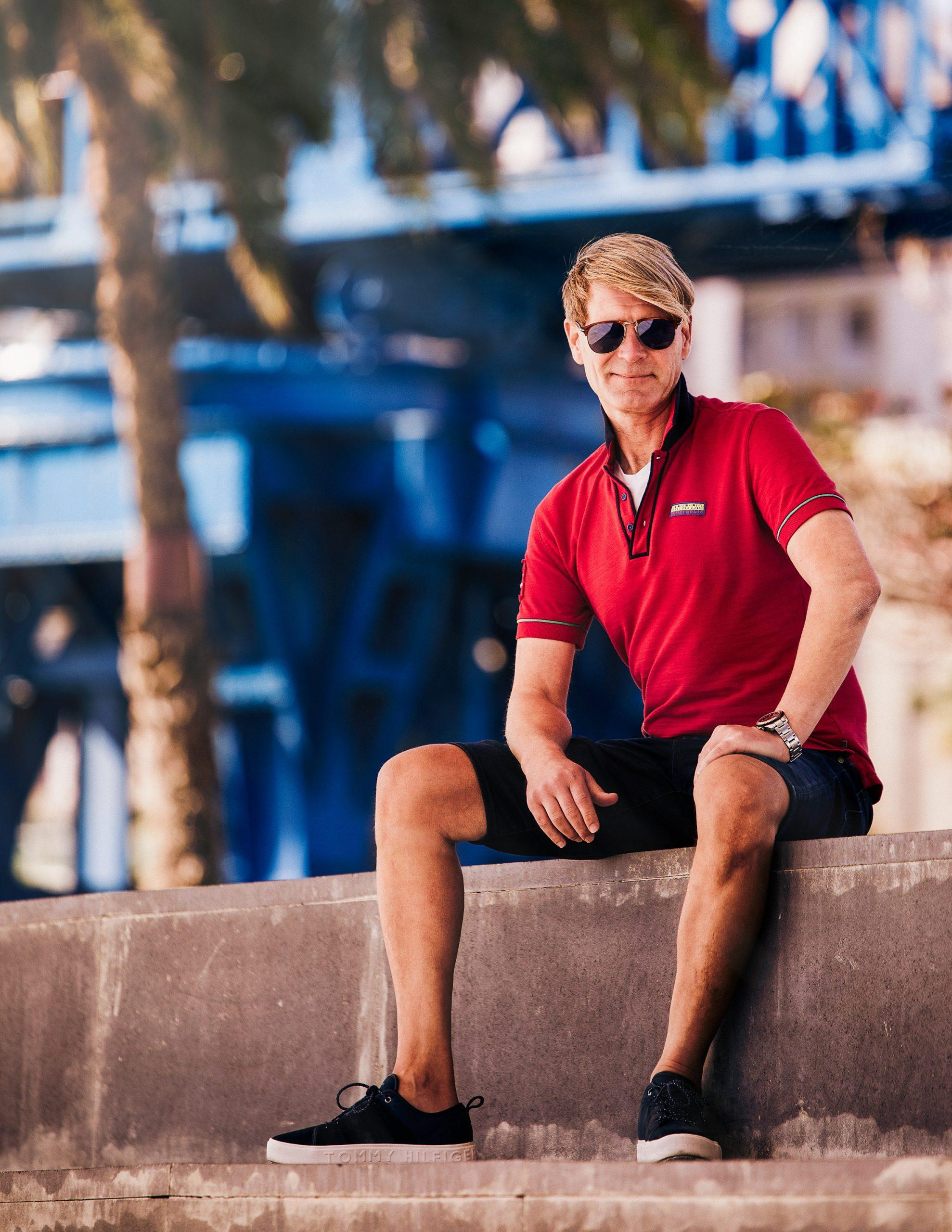 Photographer Las Palmas A man in a red polo sitting on a concrete wall.