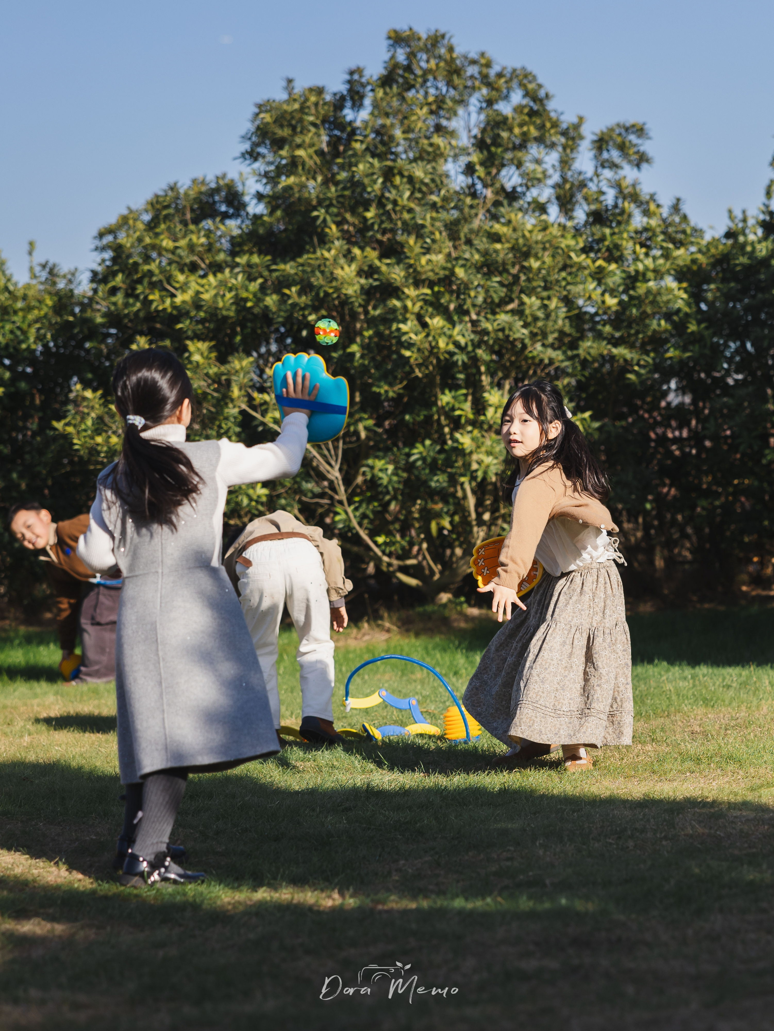 Group of children playing with ball outdoors, wide shot of birthday celebration, documentary photography