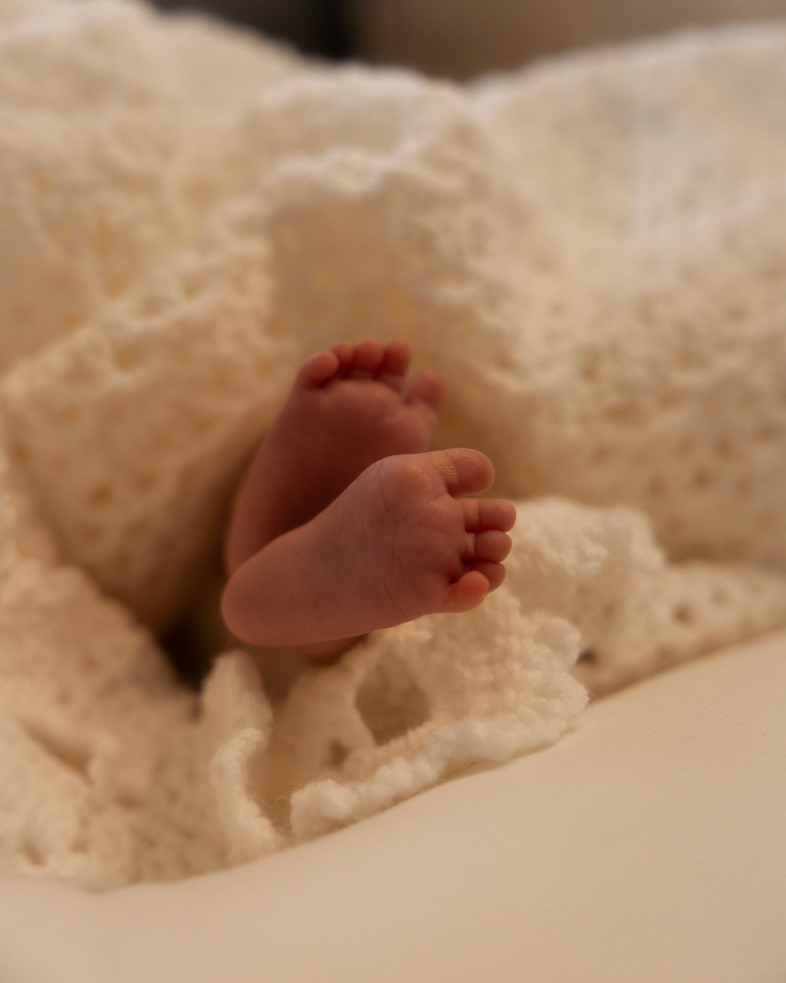Tiny baby feet resting on mother’s hands, newborn detail photography