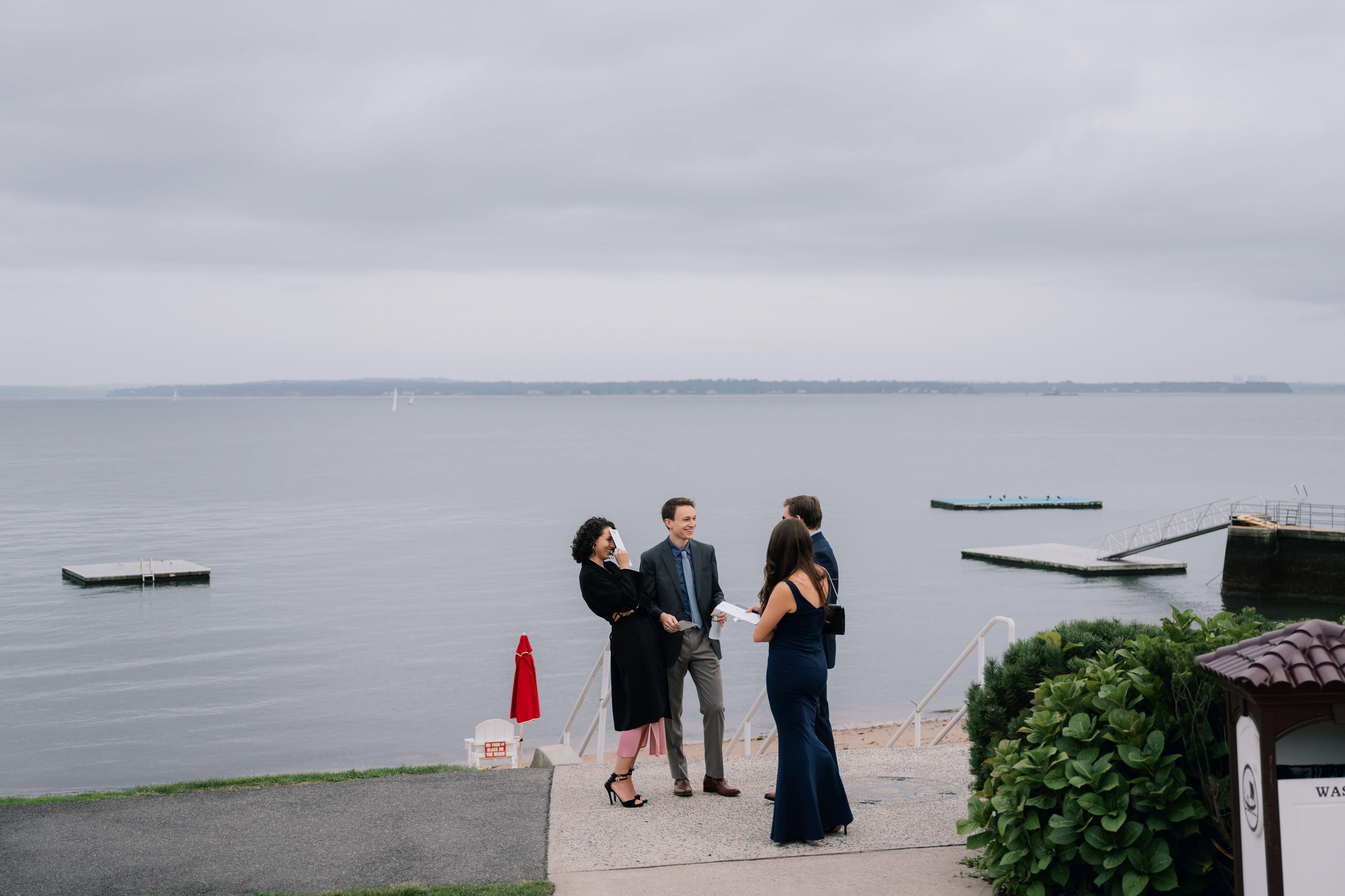a couple standing on a dock next to a body of water