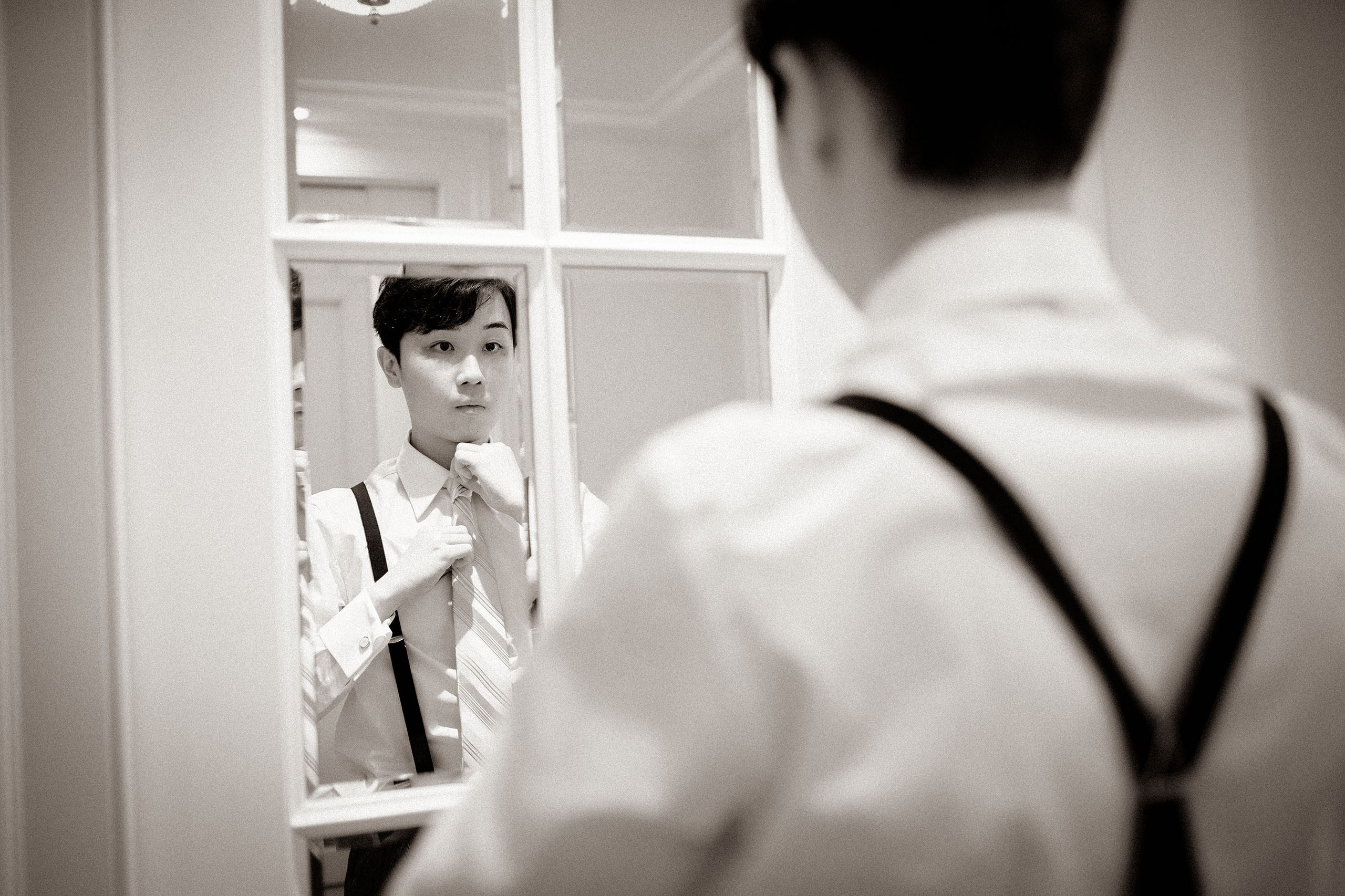 The groom checks his wardrobe in a mirror.