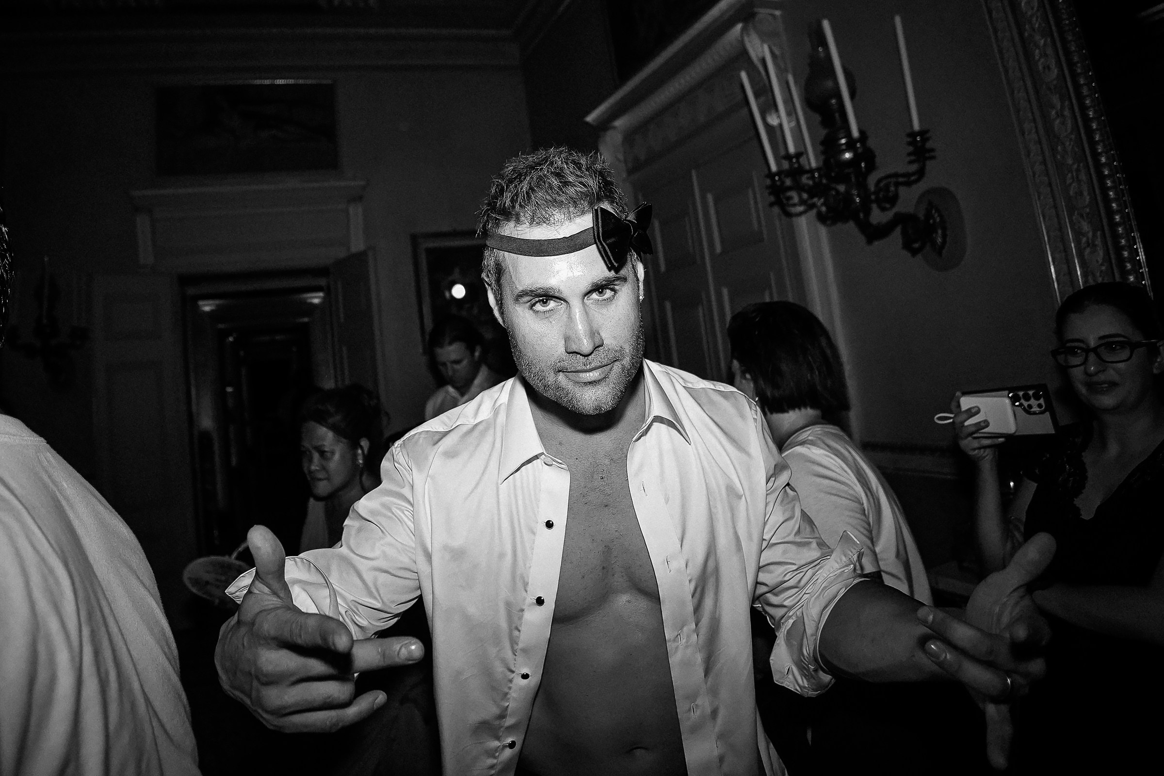 Guest with playful expression and unbuttoned shirt, embracing the carefree celebration vibe.