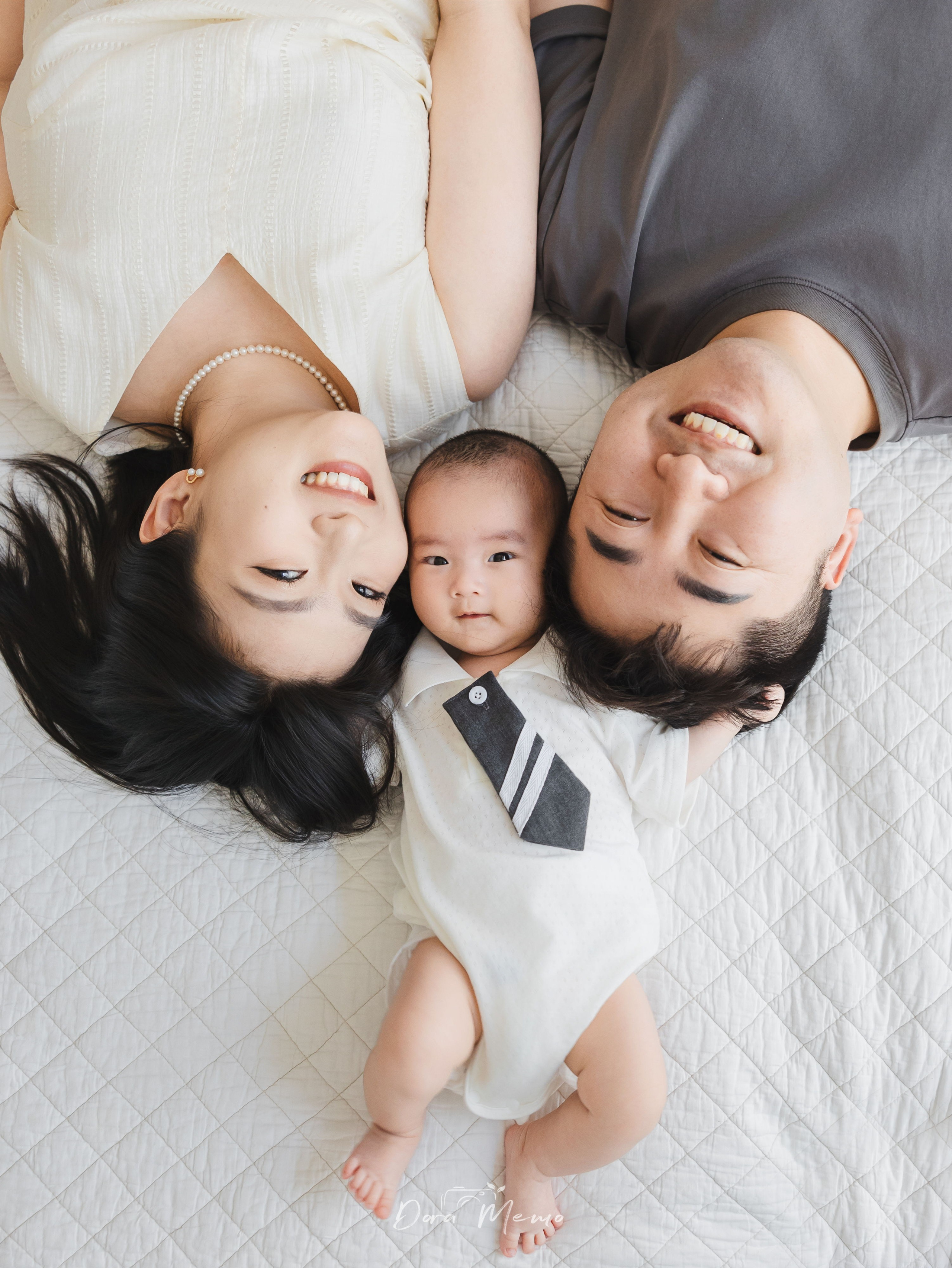 A family of three lying close together during a natural at-home photo session in Shanghai.