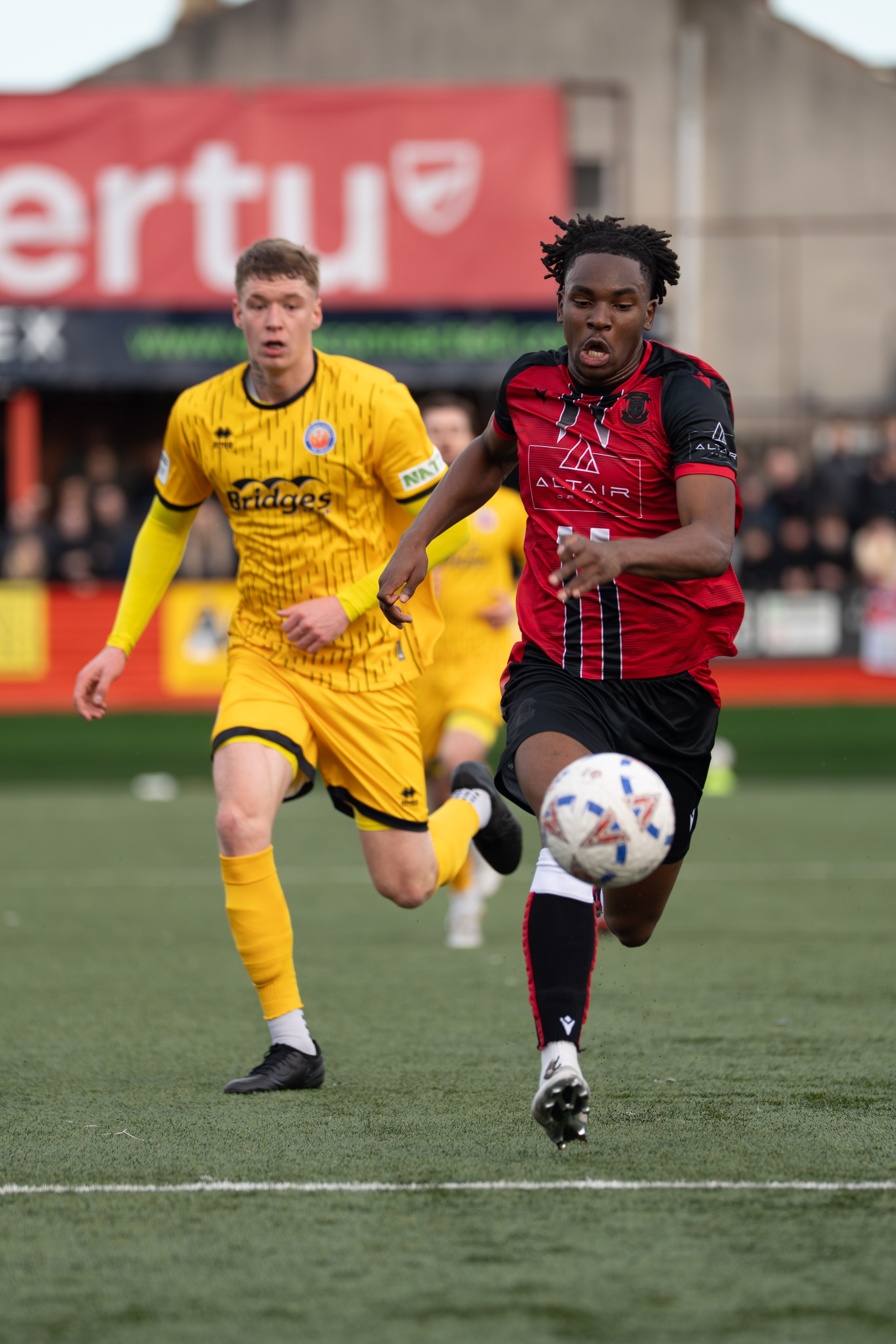 Tamworth, England — February 14, 2026: Tamworth FC’s Daniel Isichei drives forward with the ball while being pursued by an Aldershot Town player during the Enterprise National League match between Tamworth FC and Aldershot Town at The Lamb Ground. Photo: Jay Soundo