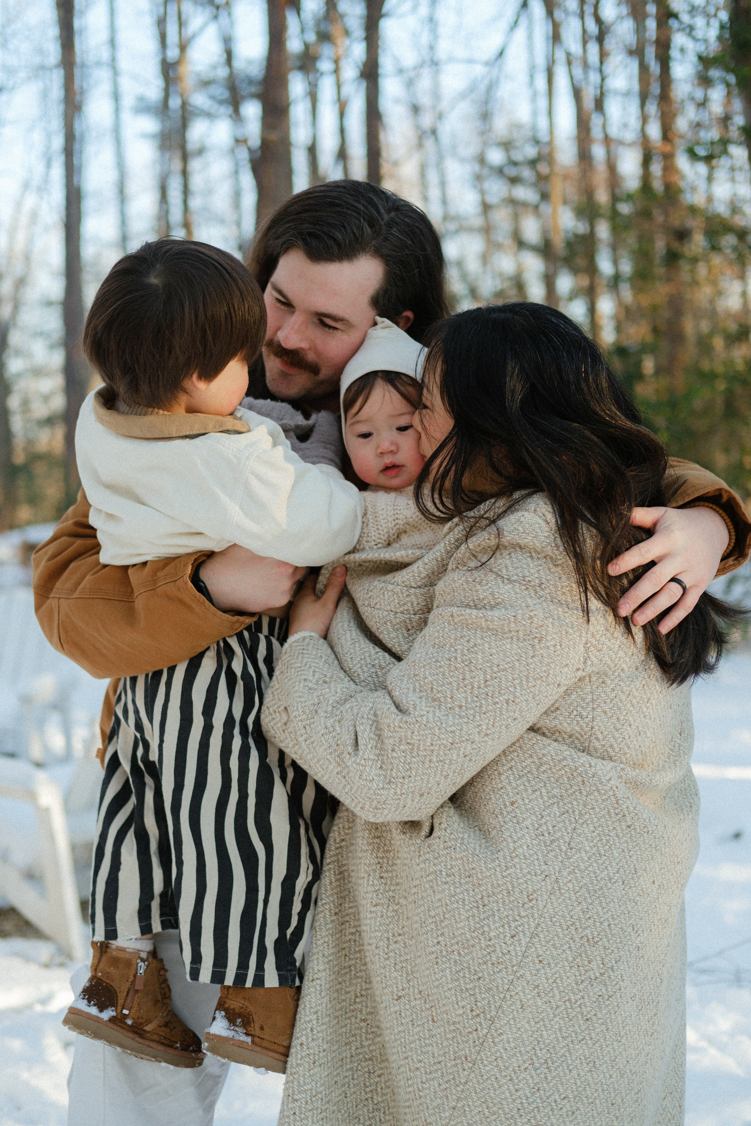 Family cuddling together in the snow near Richmond, VA — genuine joy and winter magic captured in one cozy moment.